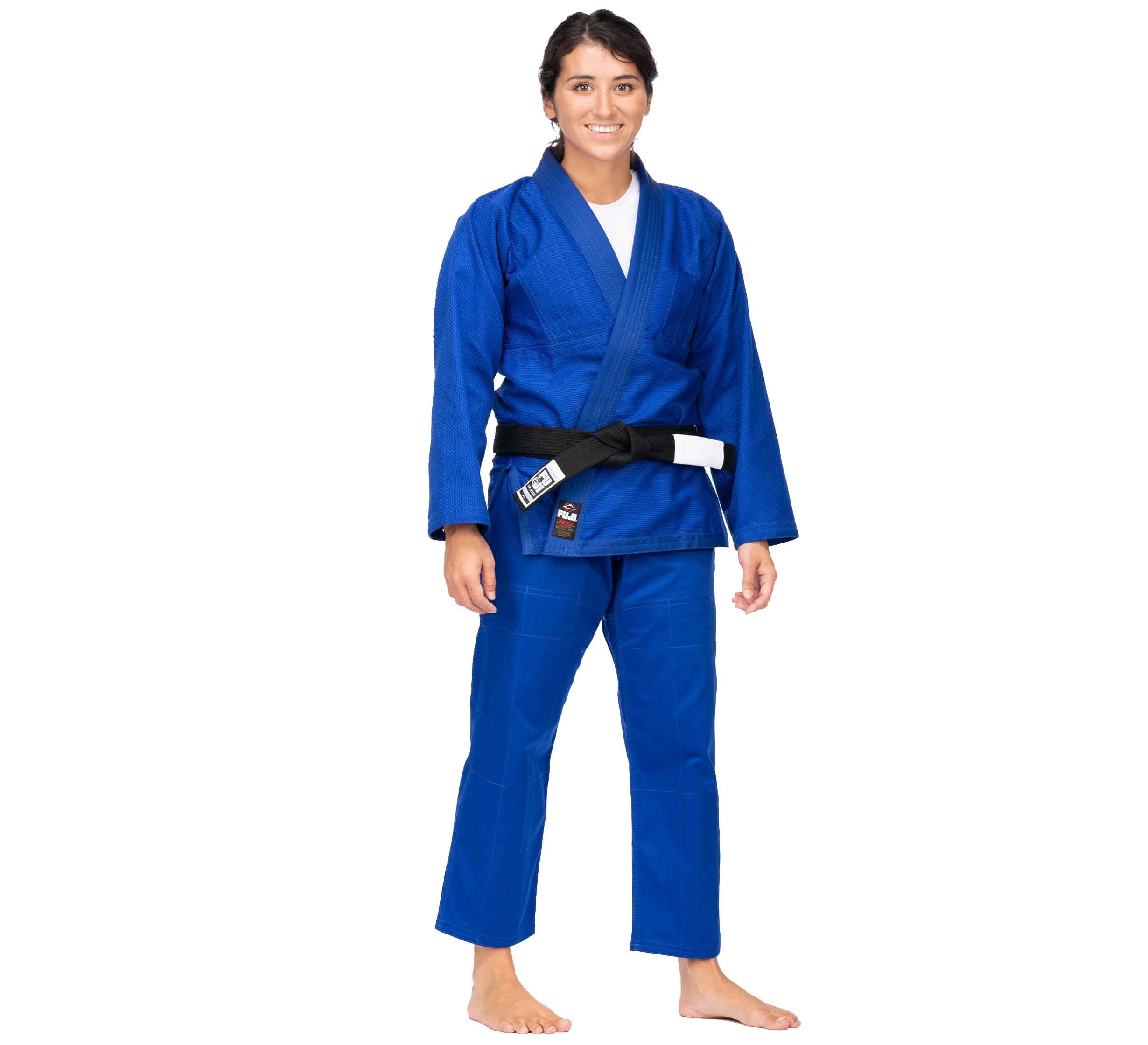 A person wears the All Around BJJ Gi Blue (Unisex Size) with a black belt, stands barefoot, and smiles against a white background.