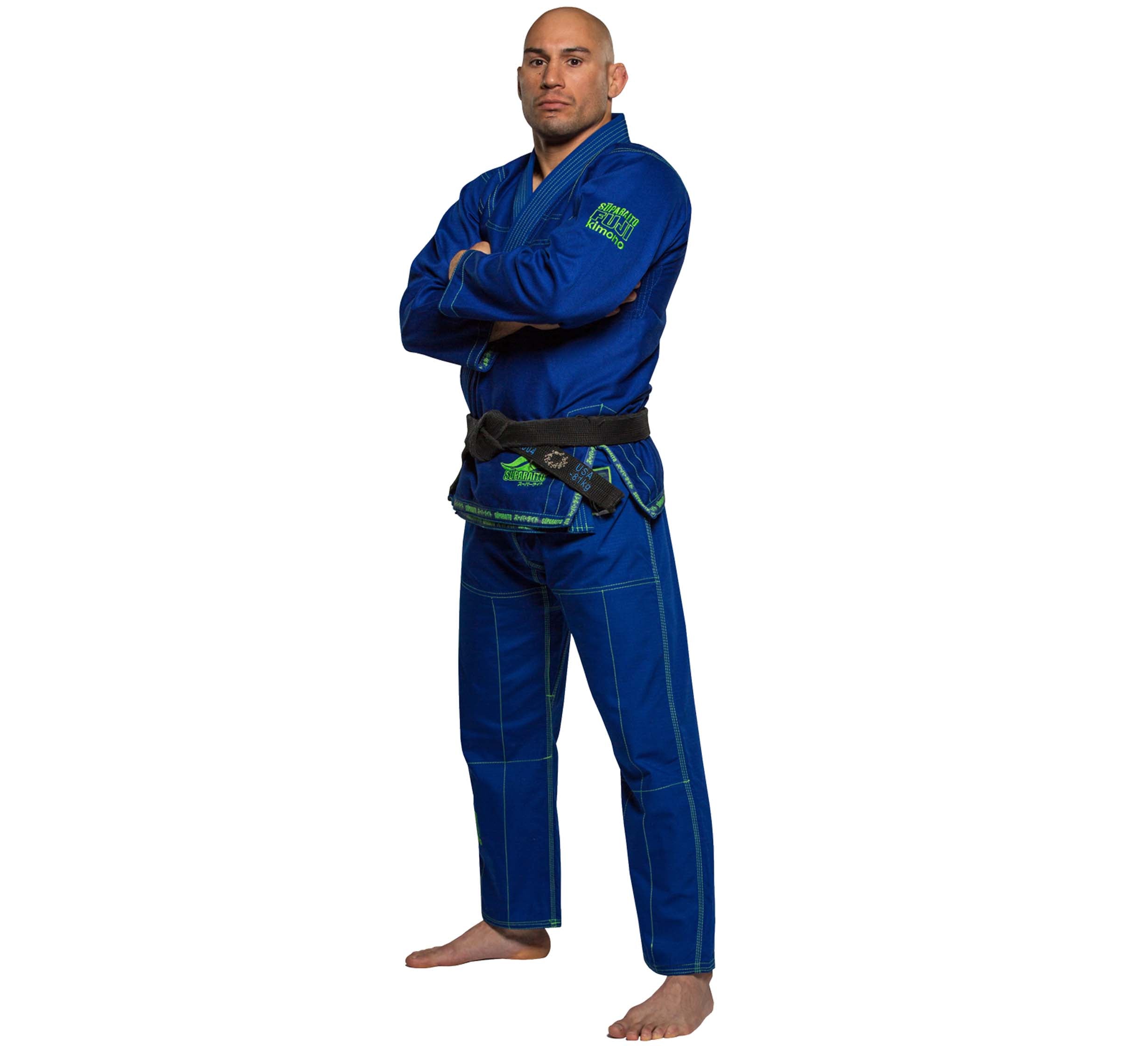 A man stands barefoot on a white background with his arms crossed, wearing the Suparaito BJJ Gi Blue and a black belt.