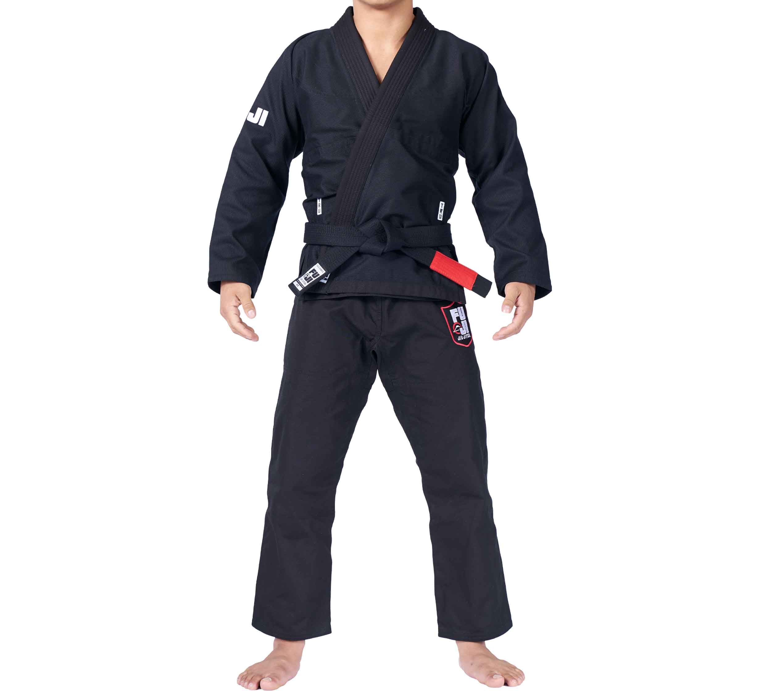A person is shown barefoot against a white background, wearing the TRU Fit BJJ Gi Bundle (2 Items) in black with patches and lettering on the sleeves and pants; their face is not visible.