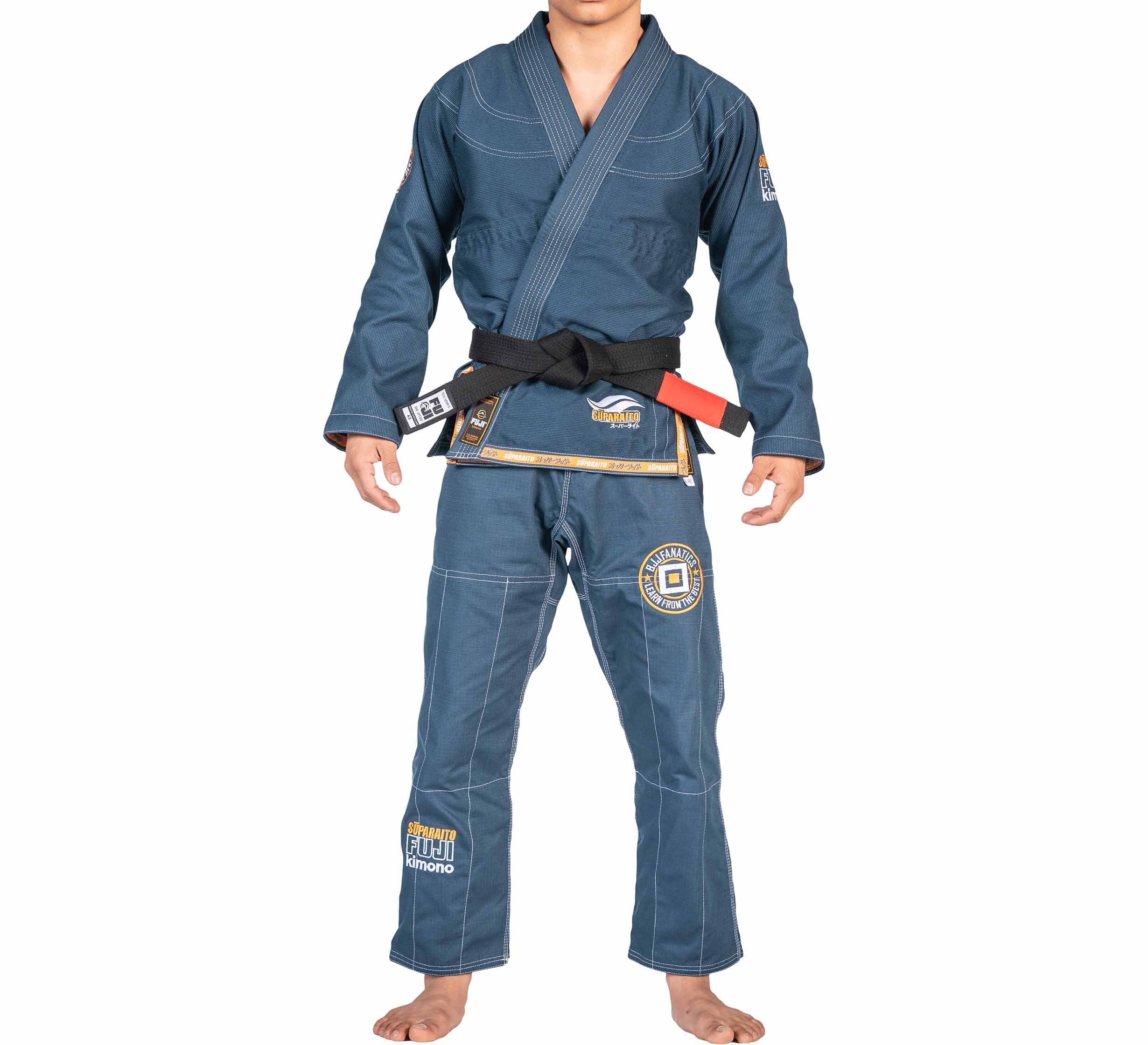 A person wearing the FUJI X BJJ Fanatics Blue Suparaito Gi with patches and a black belt stands barefoot facing forward against a white background.