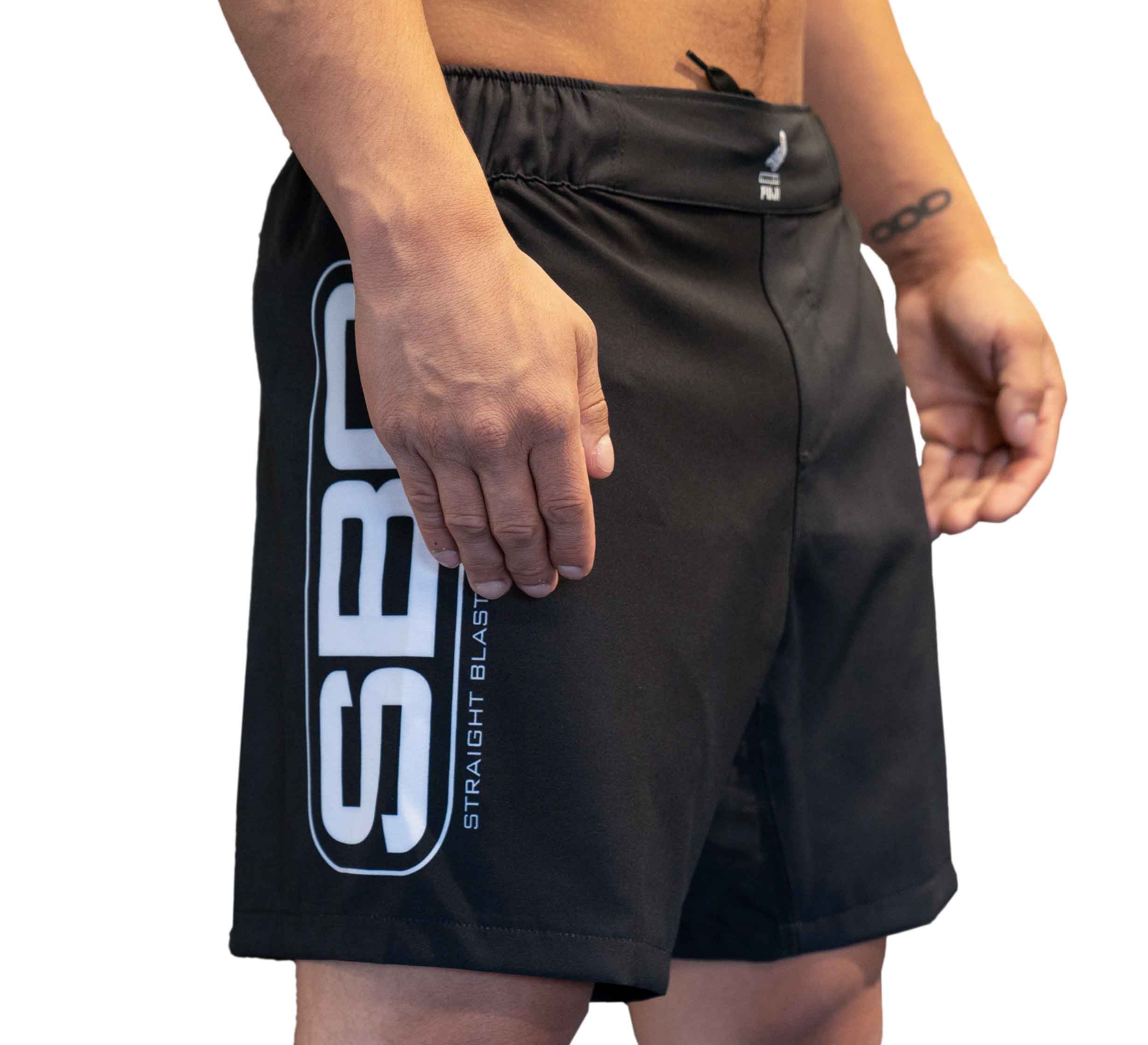 A person wears SBG Black/Grey Fight Shorts with a bold white SBG logo and "Straight Blast" on the side, standing against a plain white background.