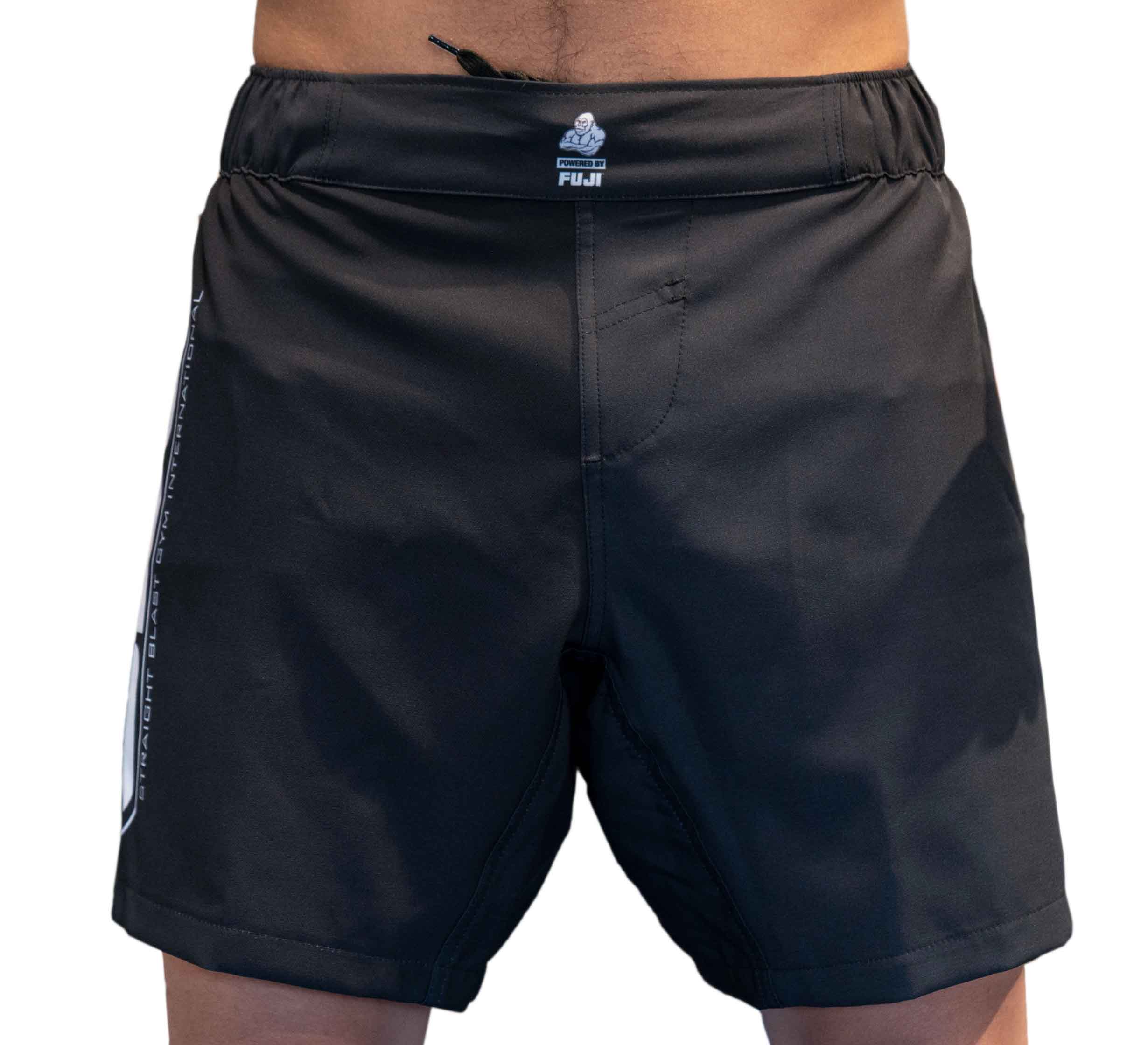 Someone wearing SBG Black/Grey Fight Shorts, featuring a FUJI logo on the waistband and white graphic accents on the sides, shown from waist to mid-thigh.