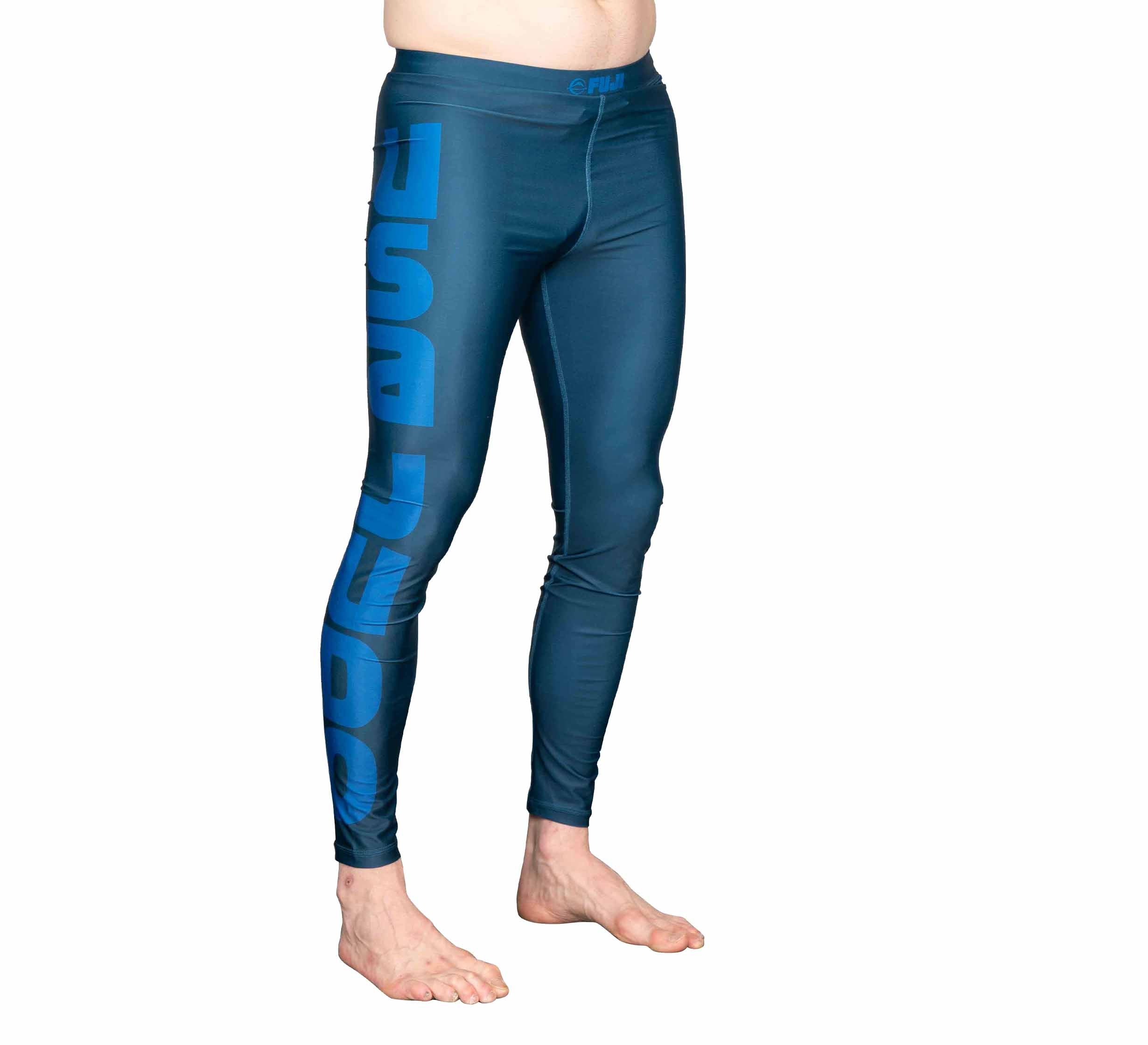 A person wearing USA Judo Spats Blue, featuring DEEP DIVE in bold blue letters on the left leg, stands barefoot against a white background.