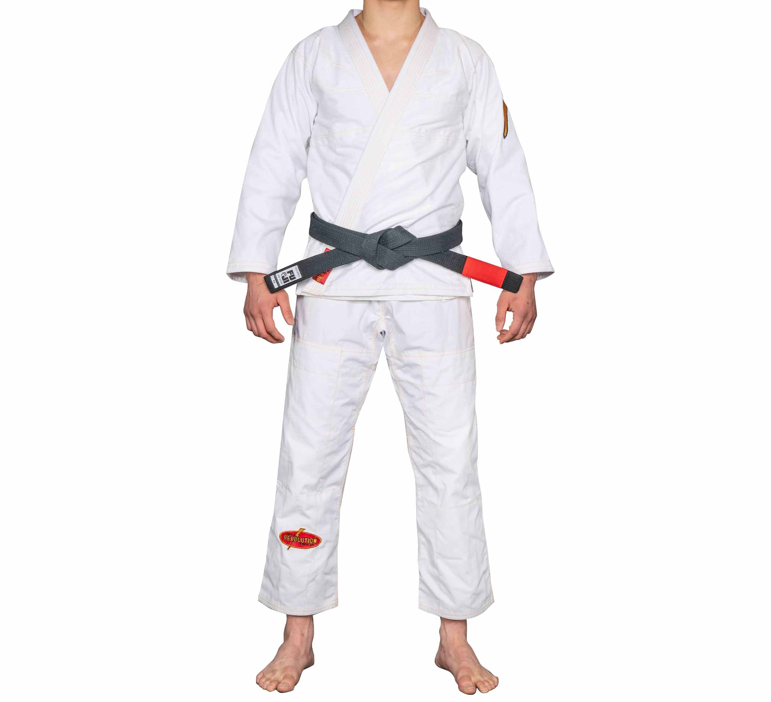 A person wearing the white BJJ Revolution Warrior Gi stands barefoot with a black belt against a plain white background.