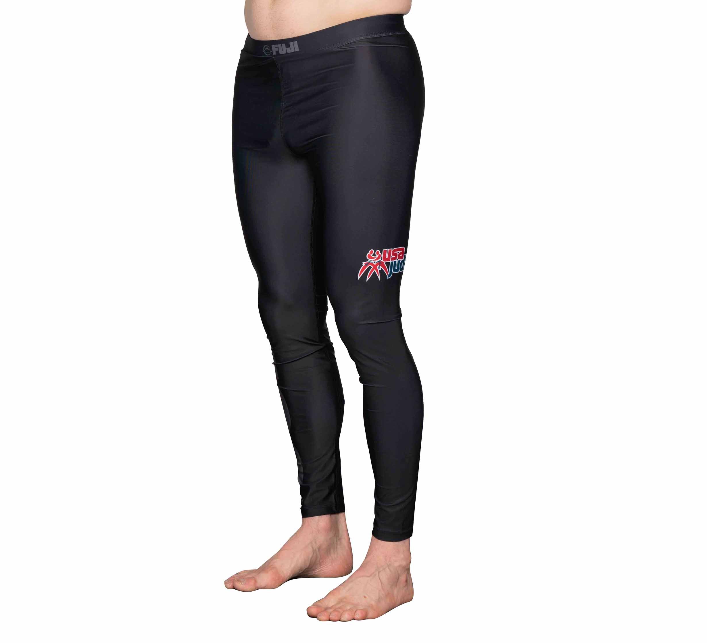 Person wearing USA Judo Spats Black, featuring black athletic compression pants with a red and white Jiu Jitsu logo on the upper left thigh, standing barefoot against a white background.