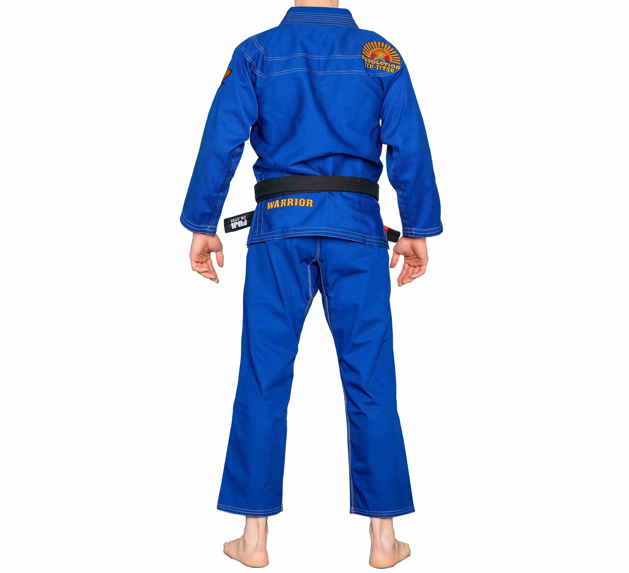 A person stands barefoot, facing away, wearing the BJJ Revolution Warrior Gi in blue with a black belt. Colorful patches are on the shoulders and back, and "WARRIOR" is visible on the belt.