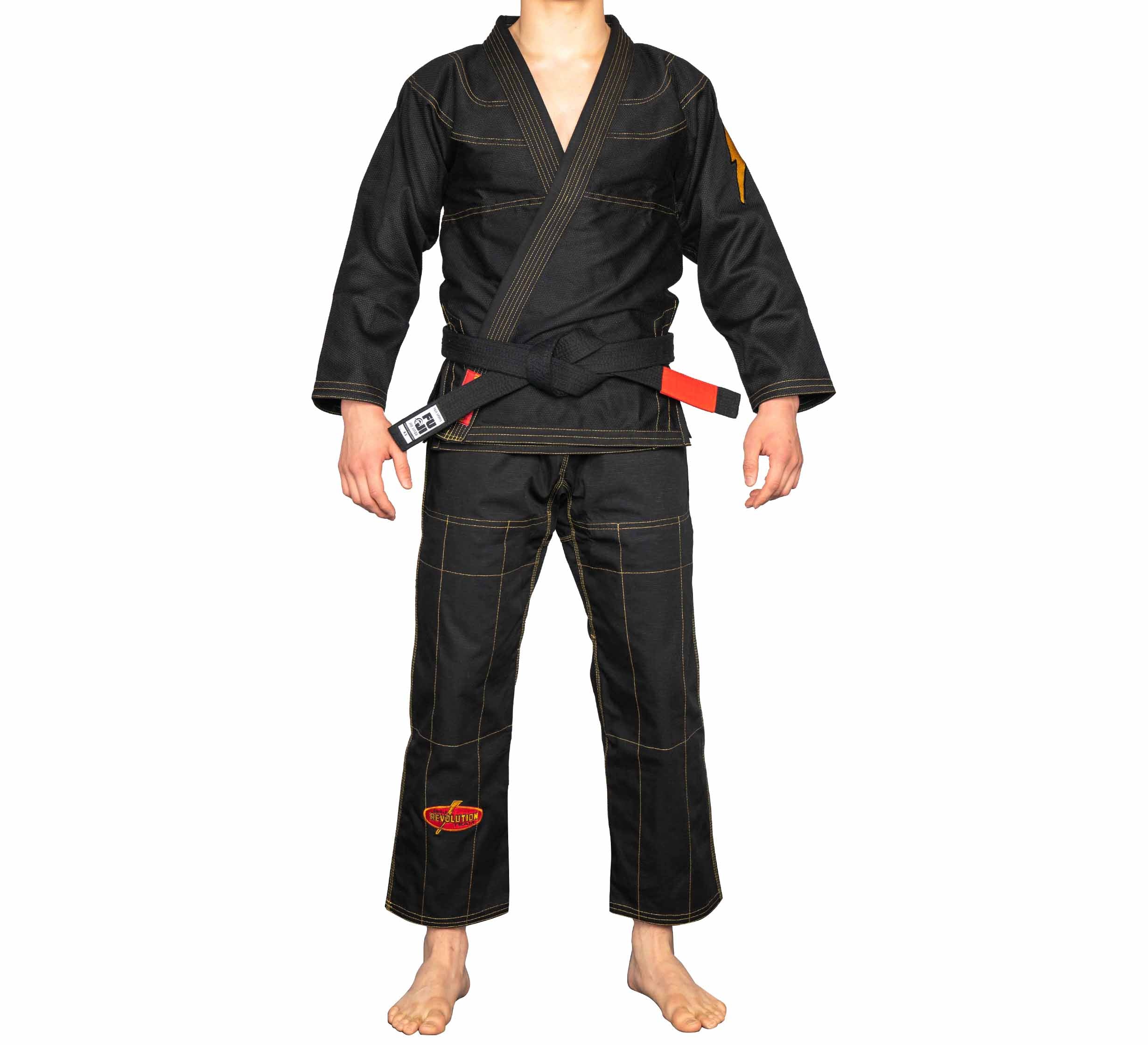 A person stands barefoot in the black BJJ Revolution Warrior Gi with a black belt, arms relaxed at their sides, shown from neck down against a white background.
