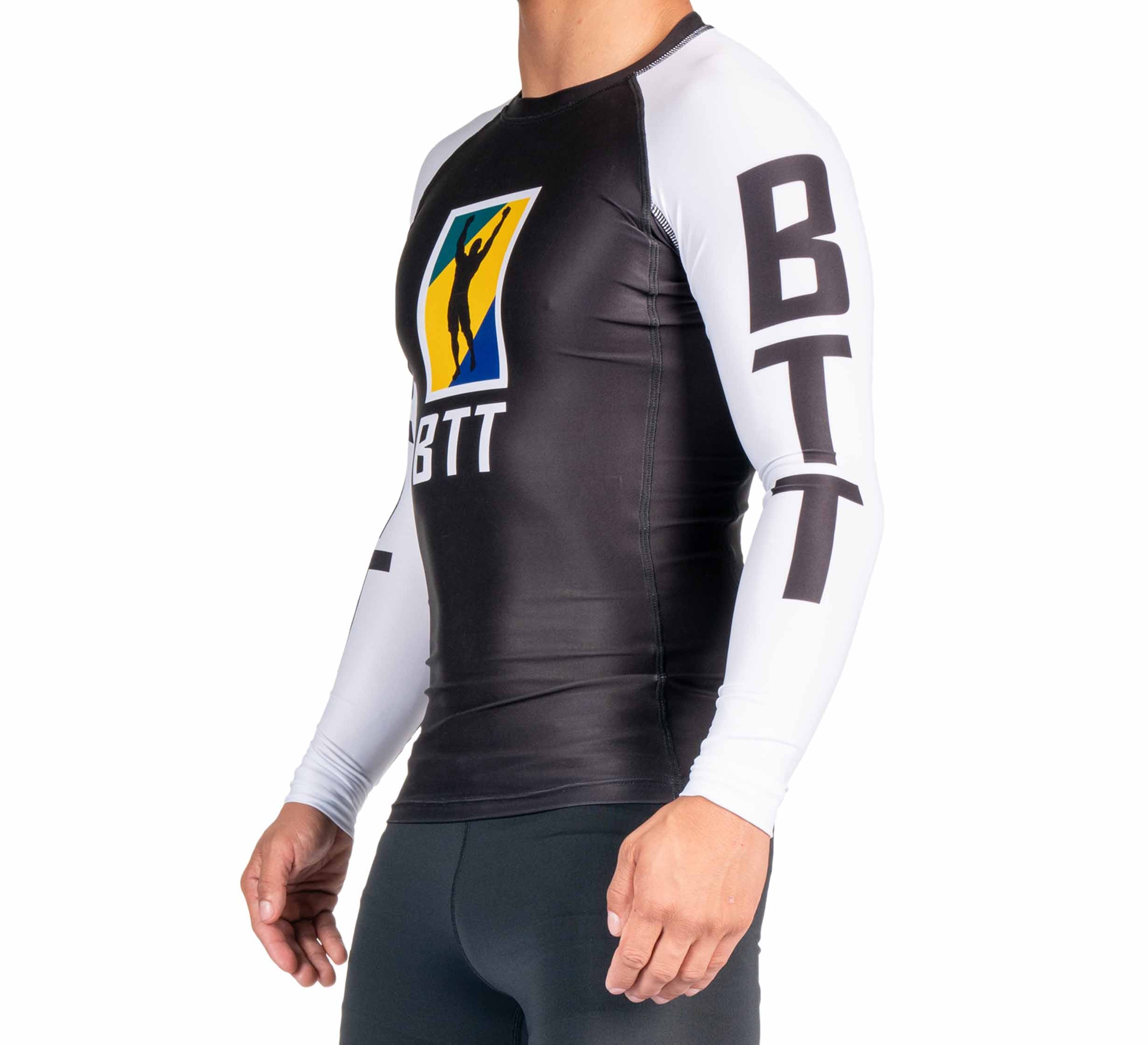 A person wearing the BTT Ranked Long Sleeve Rashguard (NEW), a black and white athletic top with BTT on the sleeves and chest, plus a colorful rectangular logo on the front.