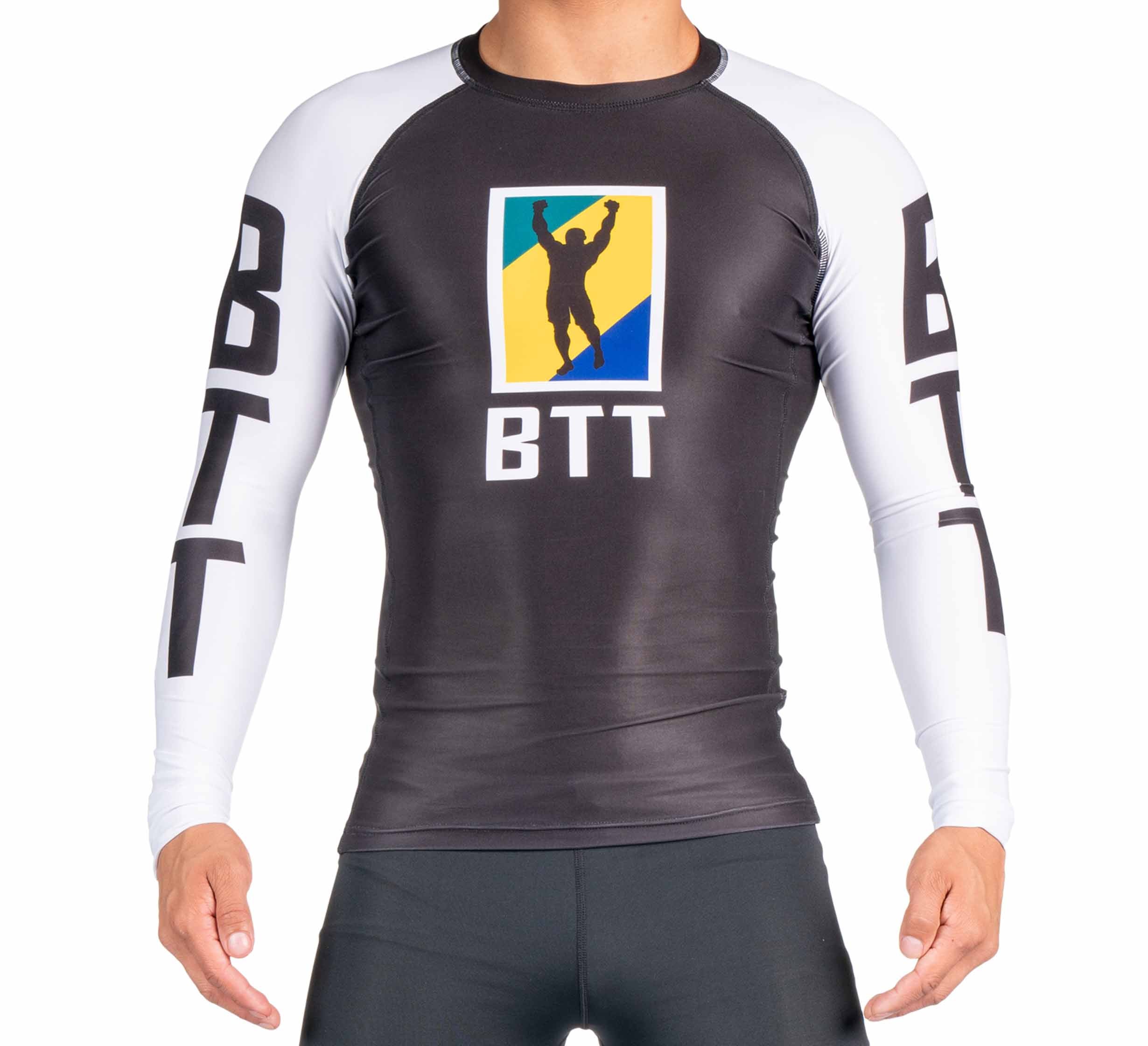 A person wears the BTT Ranked Long Sleeve Rashguard (NEW) in black and white, featuring a BTT logo with a silhouette raising their arms on the chest and "BTT" printed on the sleeves.