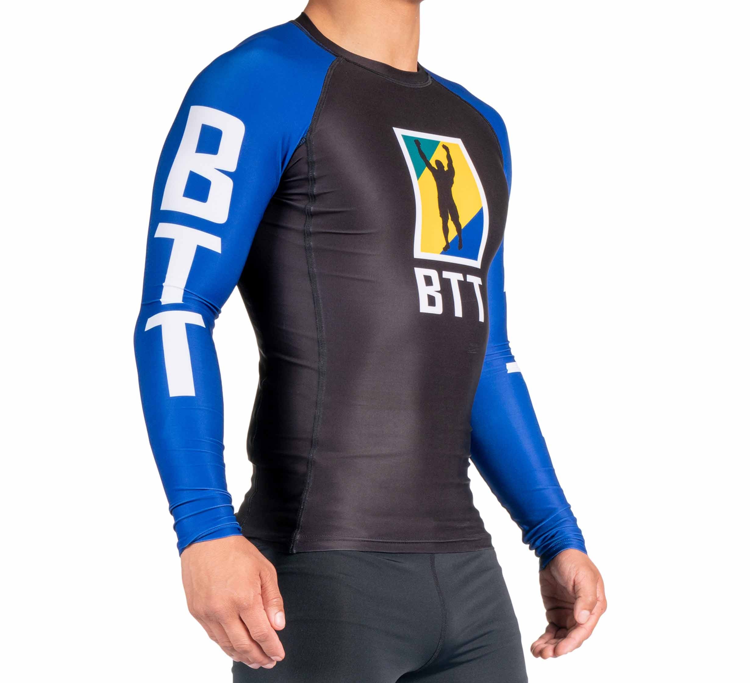 A person is wearing the BTT Ranked Long Sleeve Rashguard (NEW) in black and blue, featuring "BTT" on the sleeves and chest with a colorful logo in the center, standing against a white background.