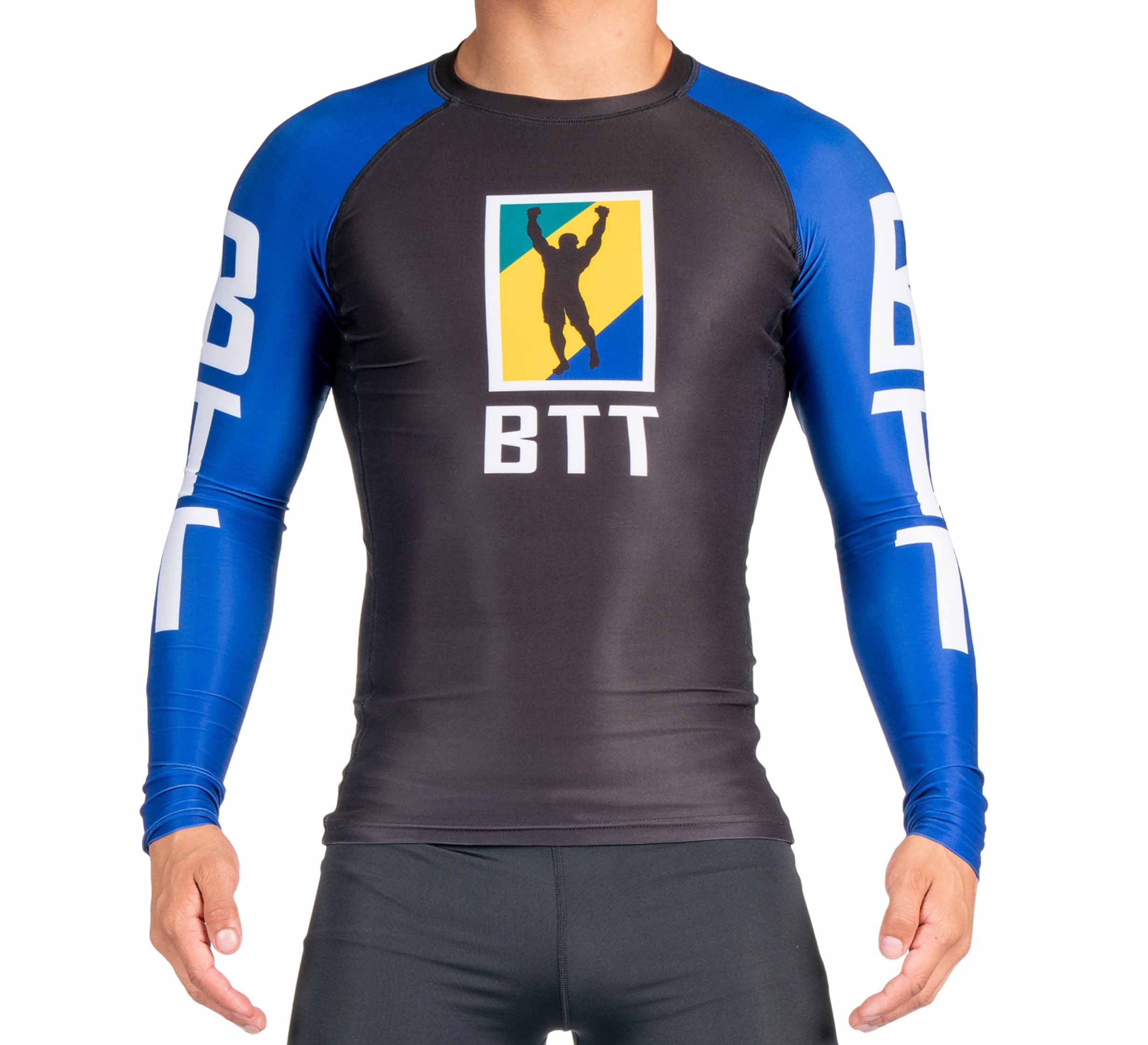 A person is wearing the BTT Ranked Long Sleeve Rashguard (NEW) in black and blue, featuring BTT and a silhouette logo on the chest, with “BTT” printed in white on the sleeves, standing with arms slightly open.