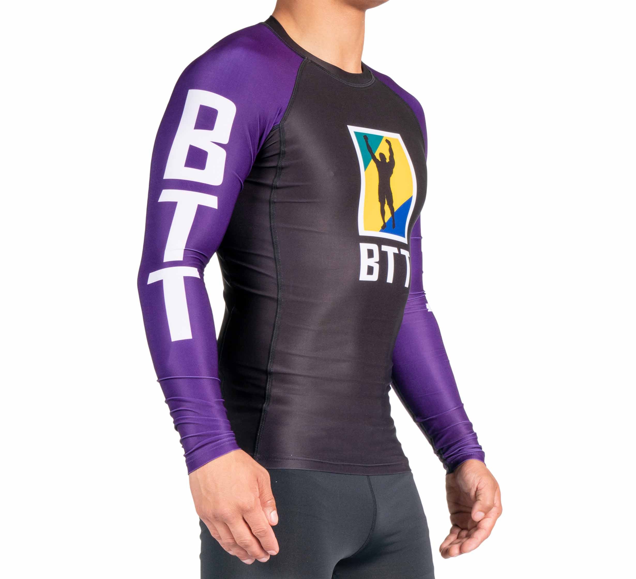 A person wearing the BTT Ranked Long Sleeve Rashguard (NEW), black and purple with BTT on the sleeves and chest, featuring a logo of a silhouette raising an arm.