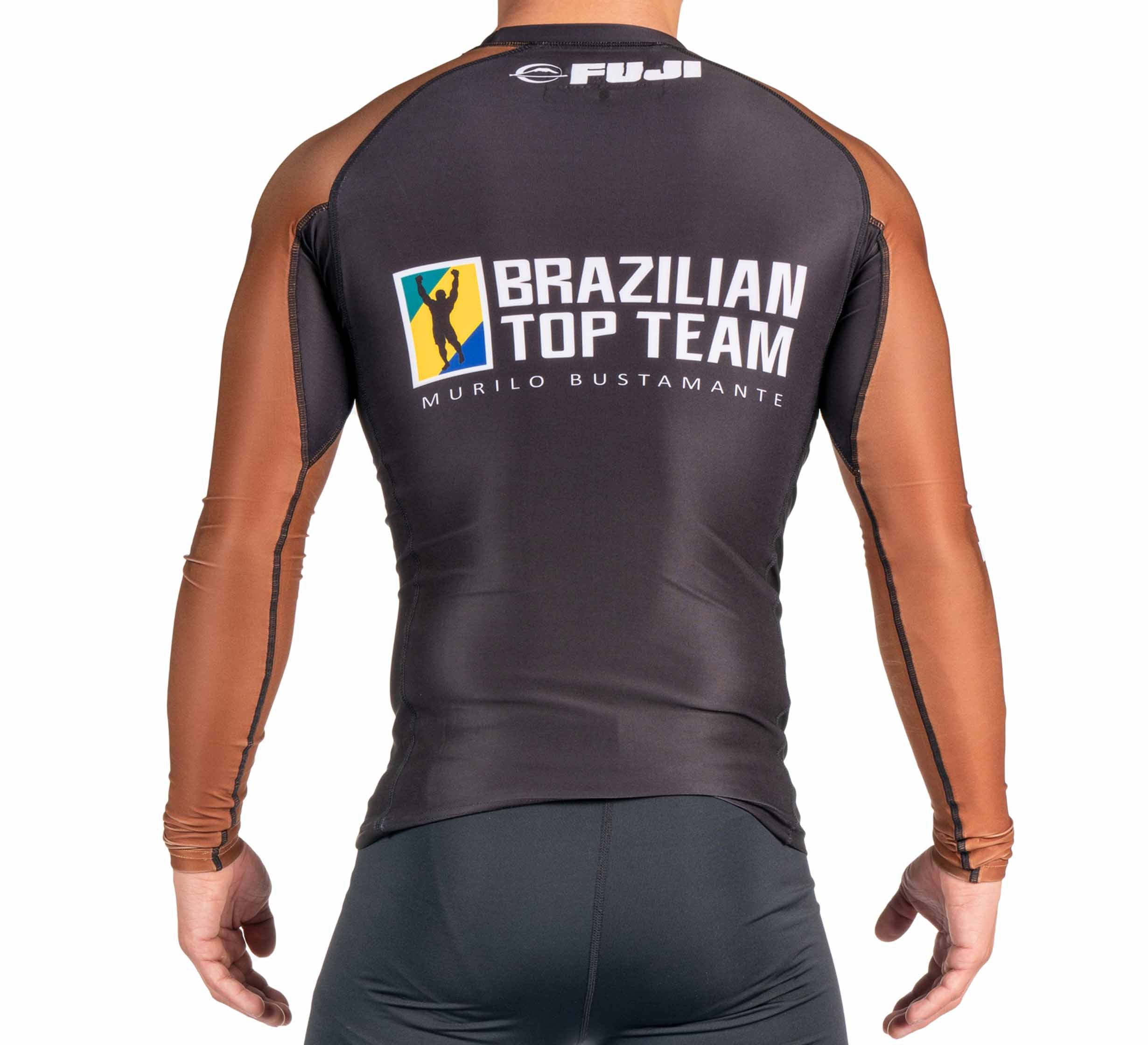 A person is shown from the back wearing the BTT Ranked Long Sleeve Rashguard (NEW), which features brown sleeves, a dark body, and FUJI plus Brazilian Top Team Murilo Bustamante logos and graphics on the back.
