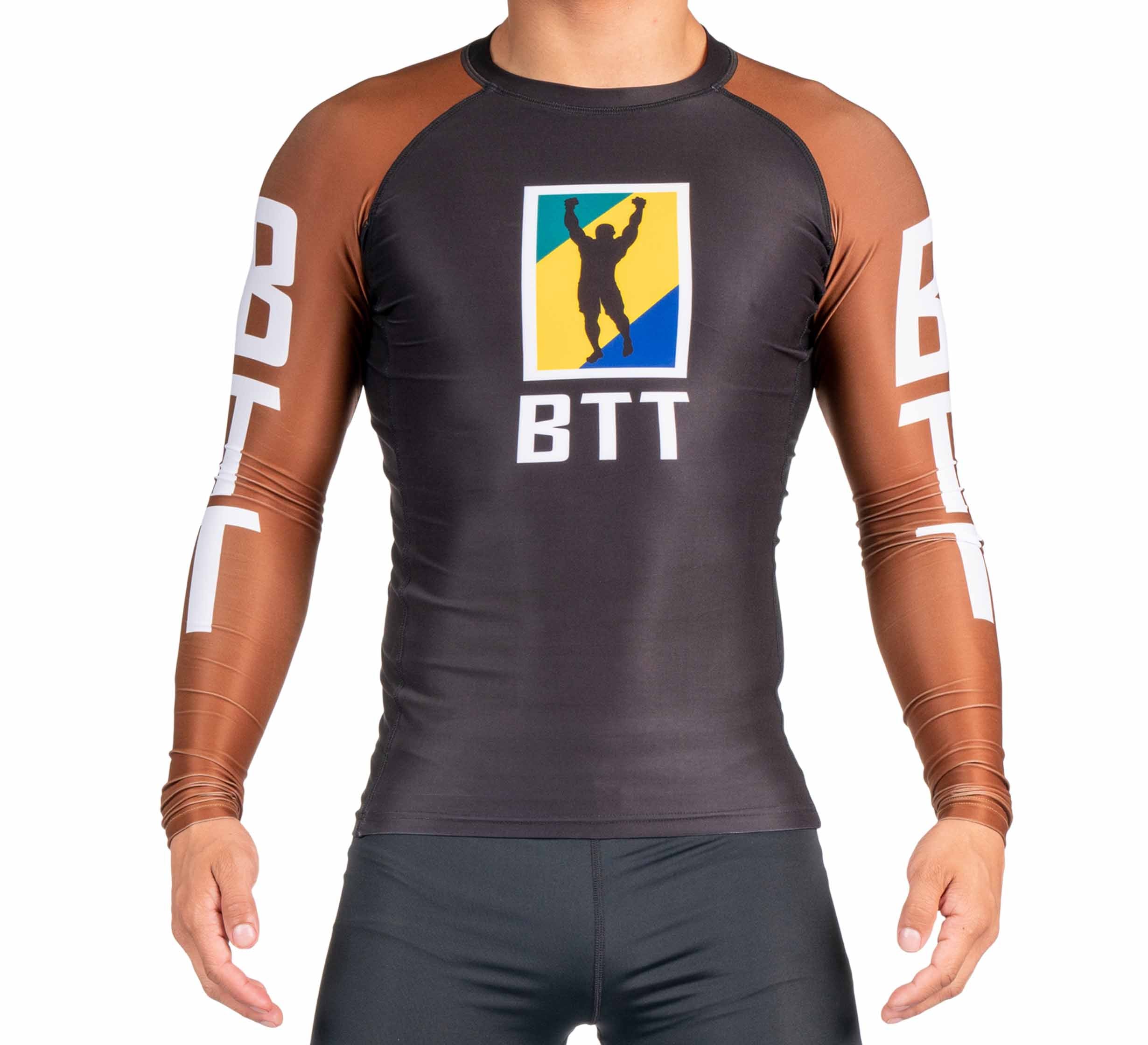 A person wearing the BTT Ranked Long Sleeve Rashguard (NEW), which has brown sleeves, a black body, and features "BTT" with a logo of a person raising their arms before a blue and yellow background.