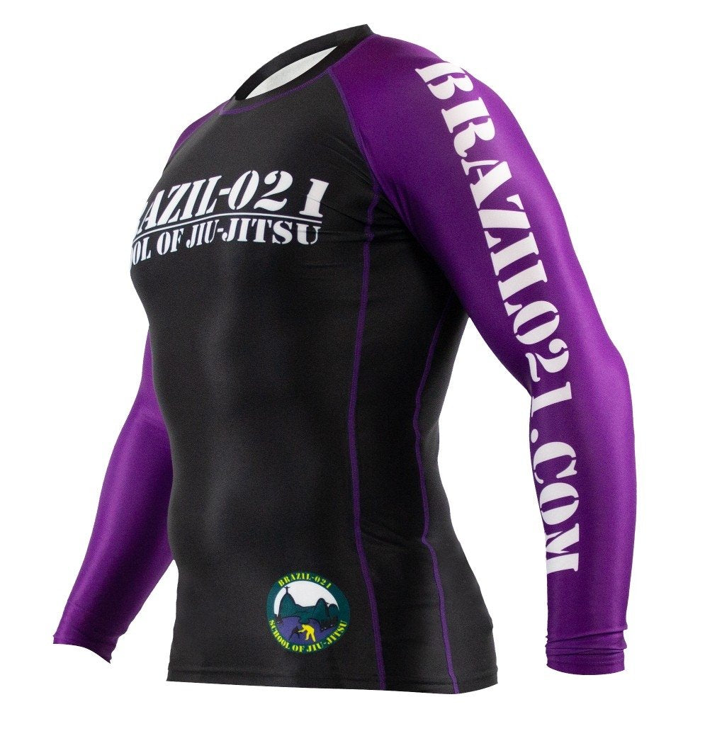The BRAZIL 021 Ranked Rashguard is a long-sleeve black and purple top with "BRAZIL-021 SCHOOL OF JIU-JITSU" on the chest, "BRAZIL021.COM" on the right sleeve, and a circular logo near the left hip.