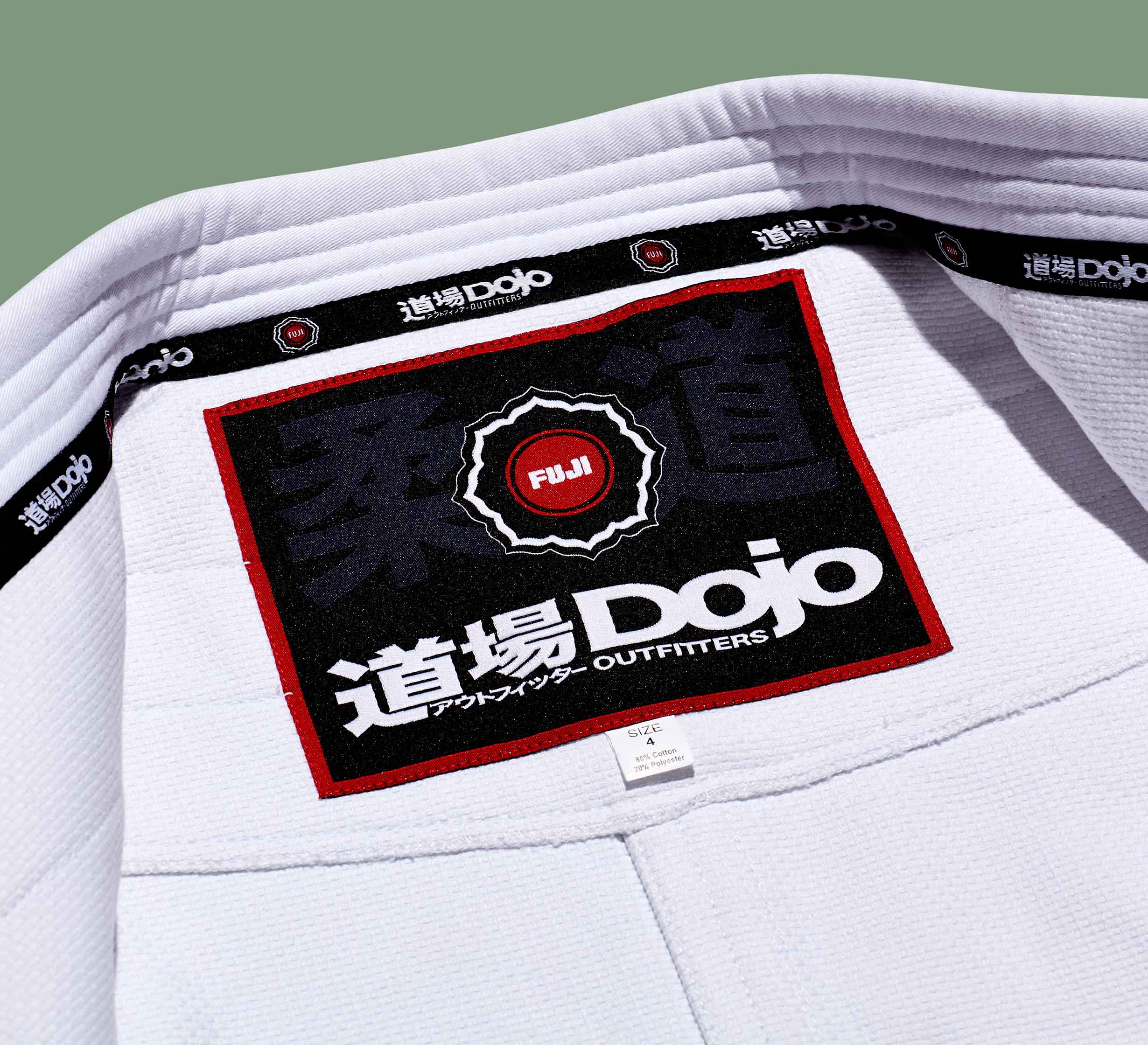 Close-up of a Dojo Outfitters x FUJI Judo Gi, showing the inside neck label with FUJI branding, Dojo Outfitters logo, Japanese characters, and a red-black design. The textured white gi fabric is clearly visible.