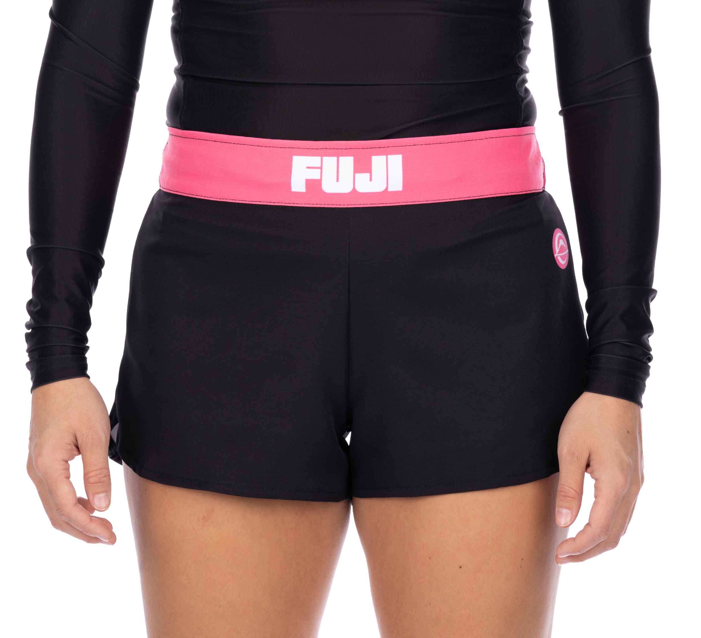 A person wearing Essential Grappling Pink Fight Shorts with a black long-sleeve top. The image is cropped from shoulders to mid-thigh.