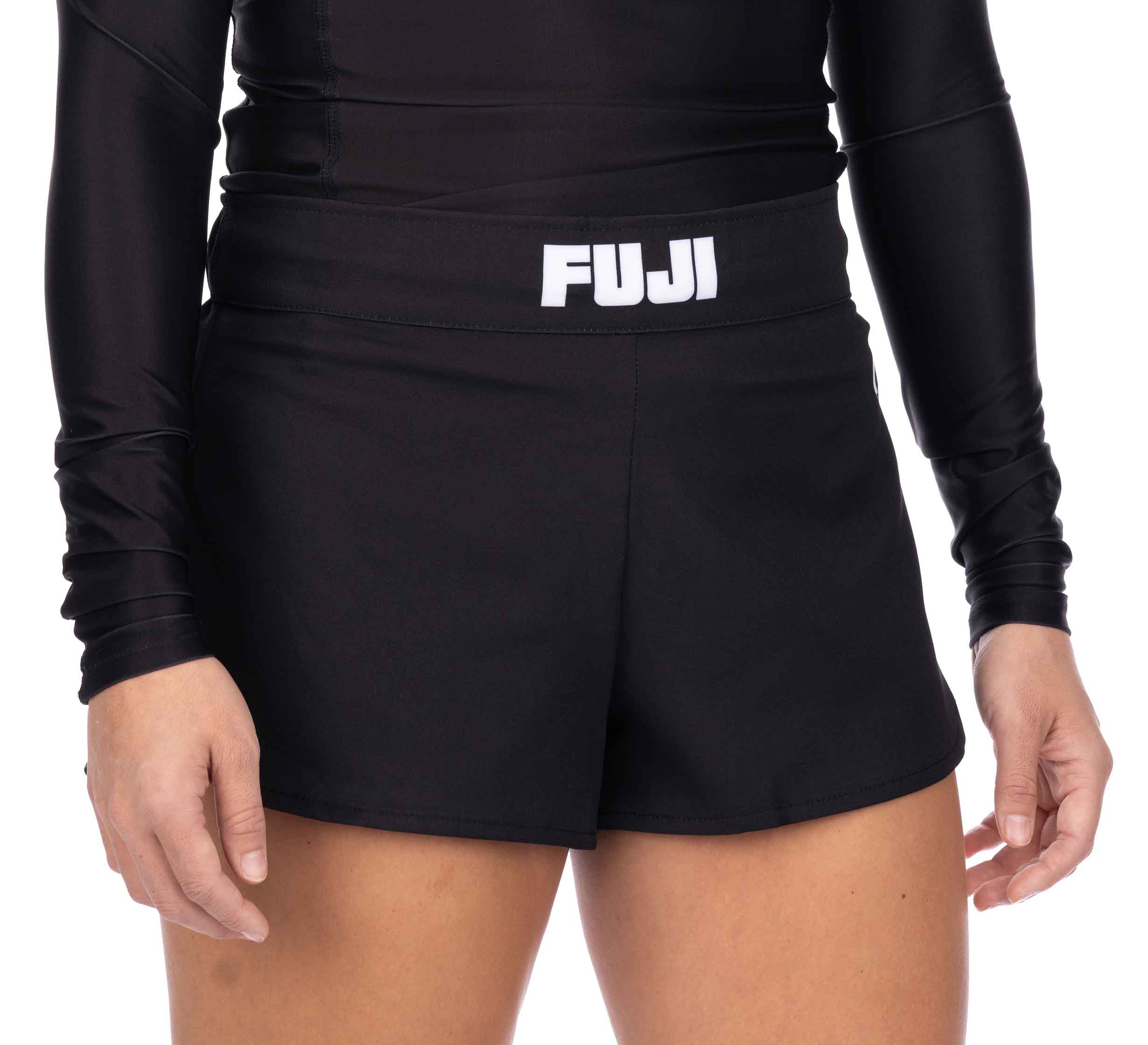A person wearing a black long-sleeve athletic top and Essential Grappling Black Fight Shorts stands with hands relaxed at their sides against a plain background.