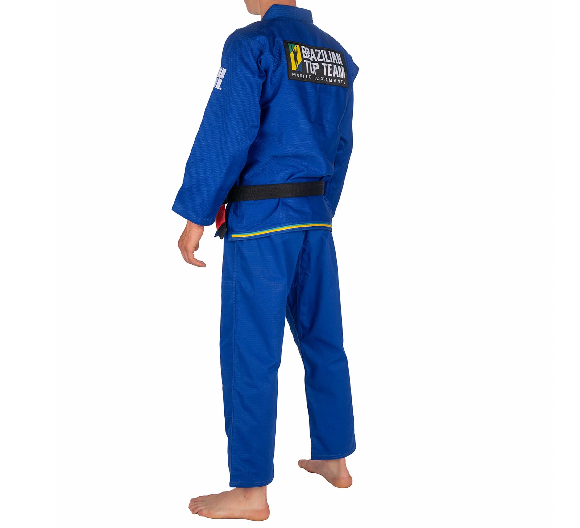 A child wears the BTT Standard Kids Gi - Blue, barefoot and facing away to display the Brazilian Top Team logo on the back, against a white background.