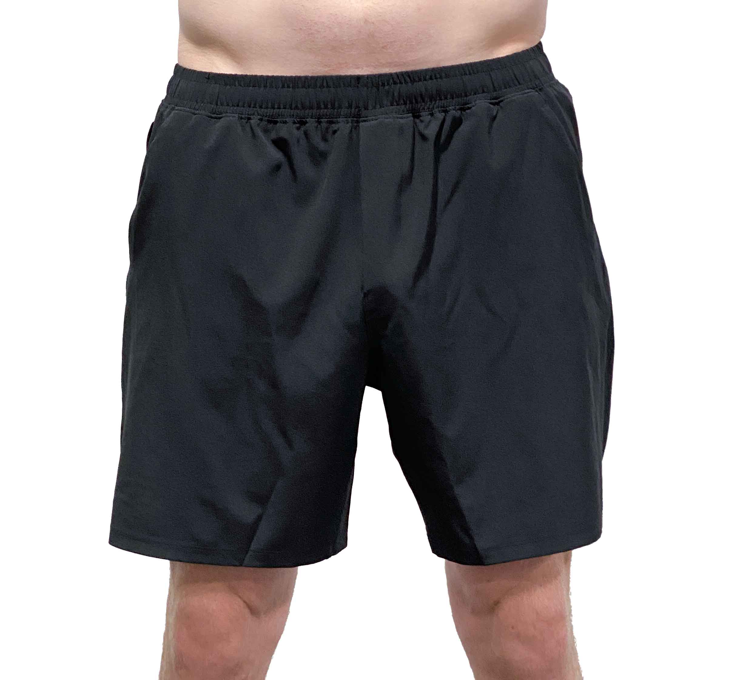 A person models the Commuter Workout Shorts—black athletic shorts with an elastic waistband—against a plain white background, showing only their lower torso and legs.