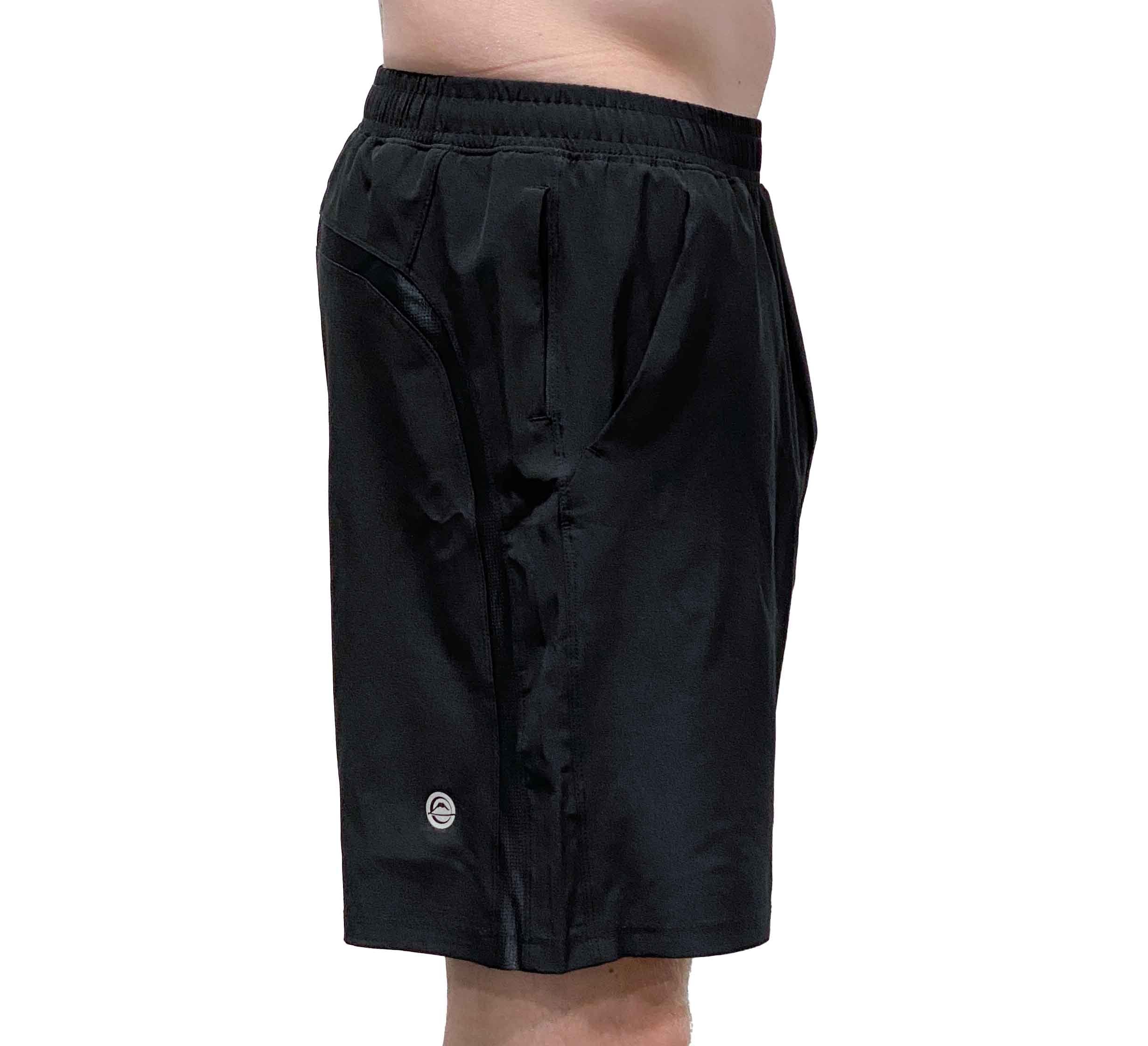 A person wearing Commuter Workout Shorts—black with an elastic waistband, side pockets, and a small circular logo near the hem—shown from the side against a white background.