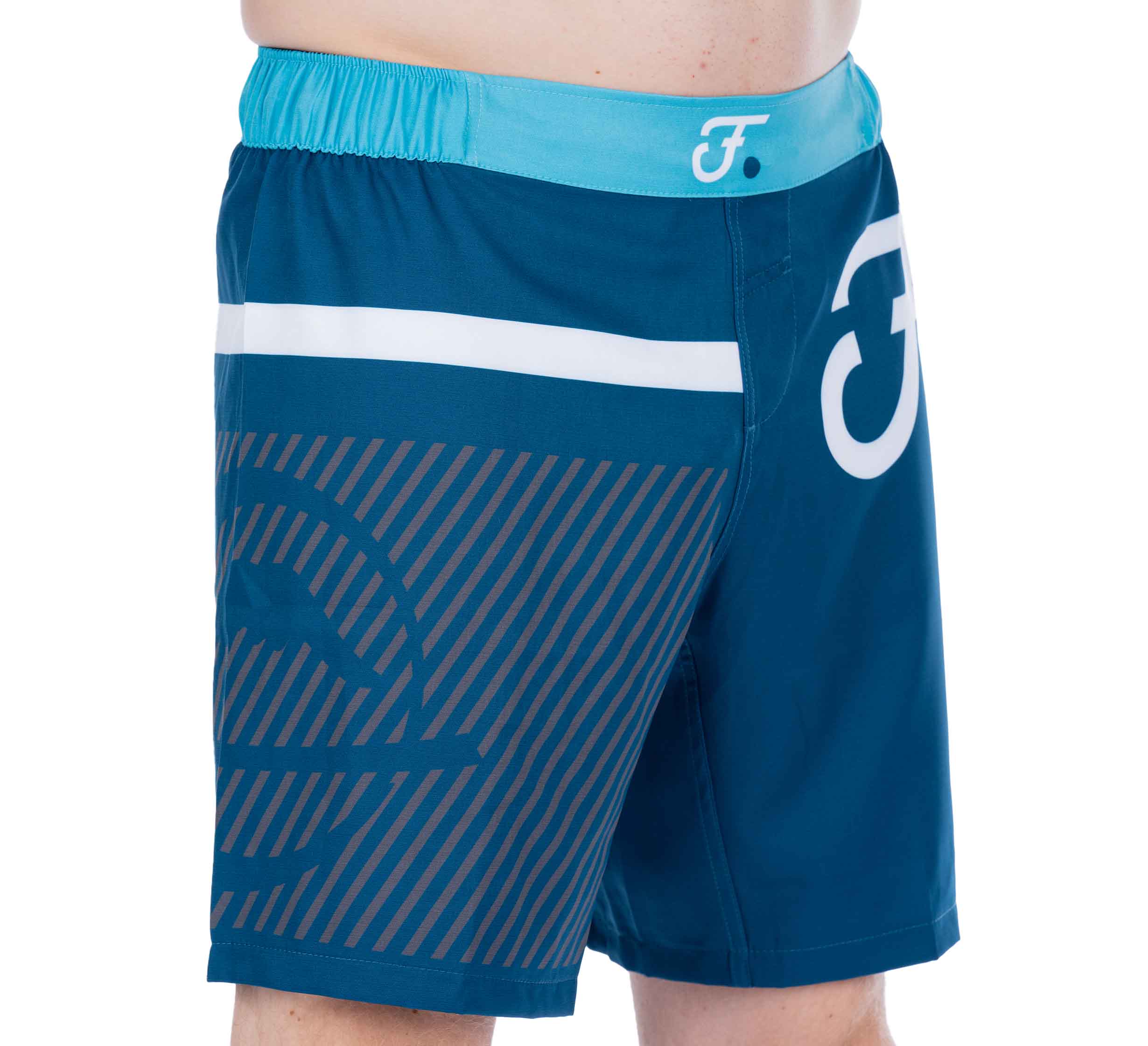 A person wearing Script Grappling Shorts Blue, featuring a white stripe, abstract logo, and diagonal lines pattern. Only the lower torso and upper legs are visible.