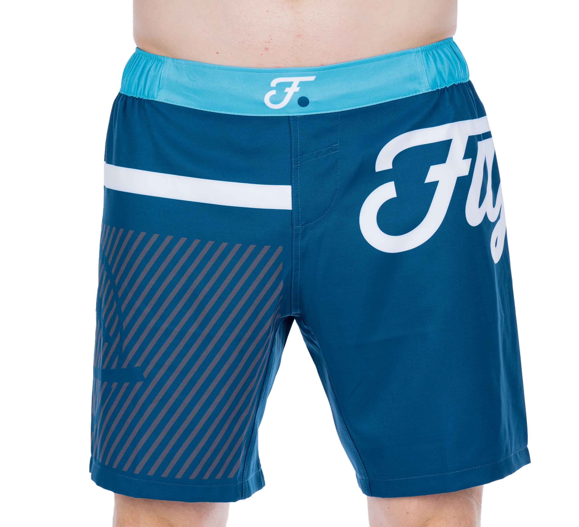 A person wearing Script Grappling Shorts Blue featuring a turquoise waistband, white Fly logo on the right thigh, diagonal stripes on the left leg, and a horizontal white stripe near the waist.