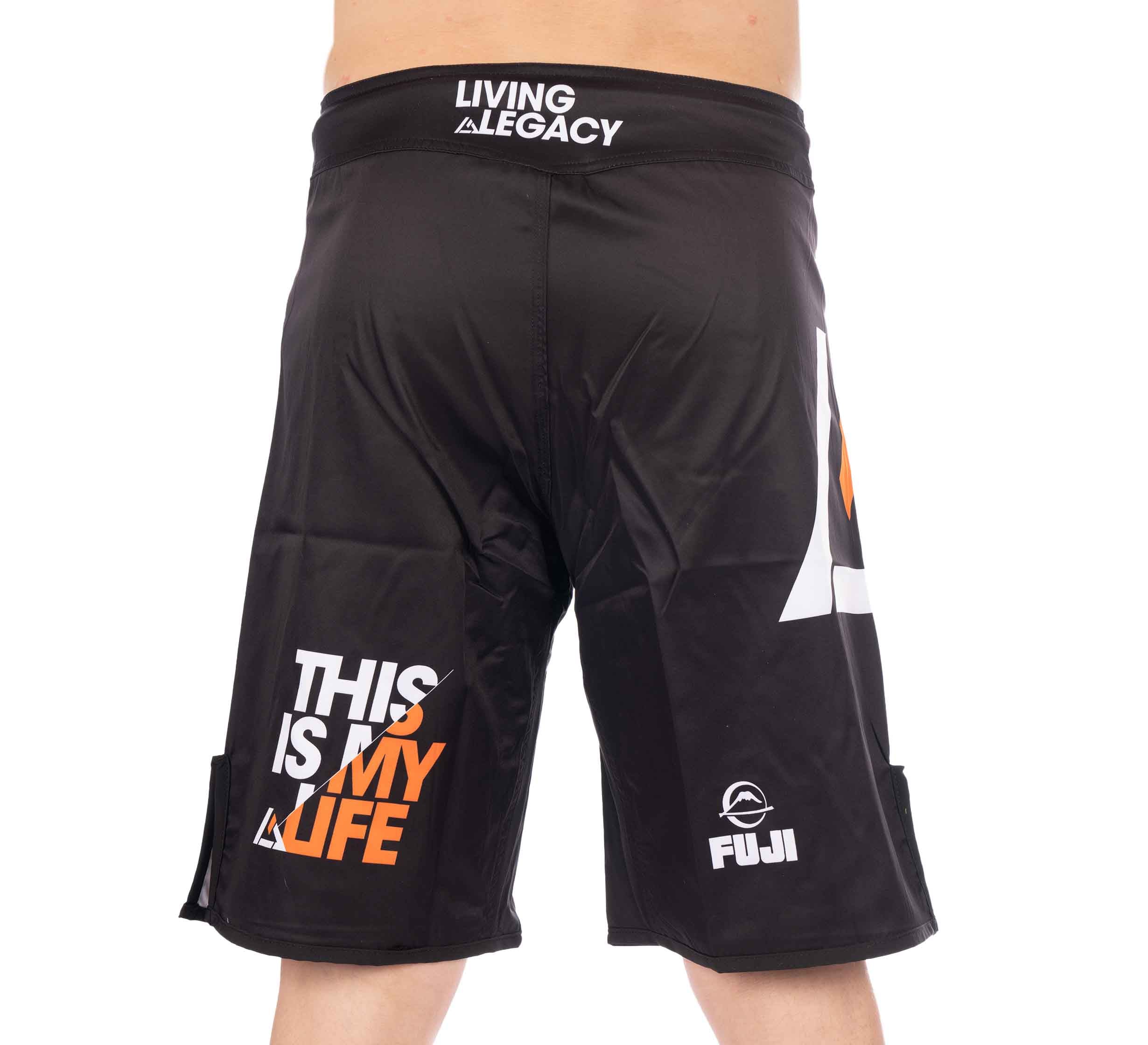 A person seen from behind wearing Rilion Gracie Black Fight Shorts, featuring bold white and orange text reading "THIS IS MY LIFE," along with "LIVING A LEGACY" and the Fuji logo.