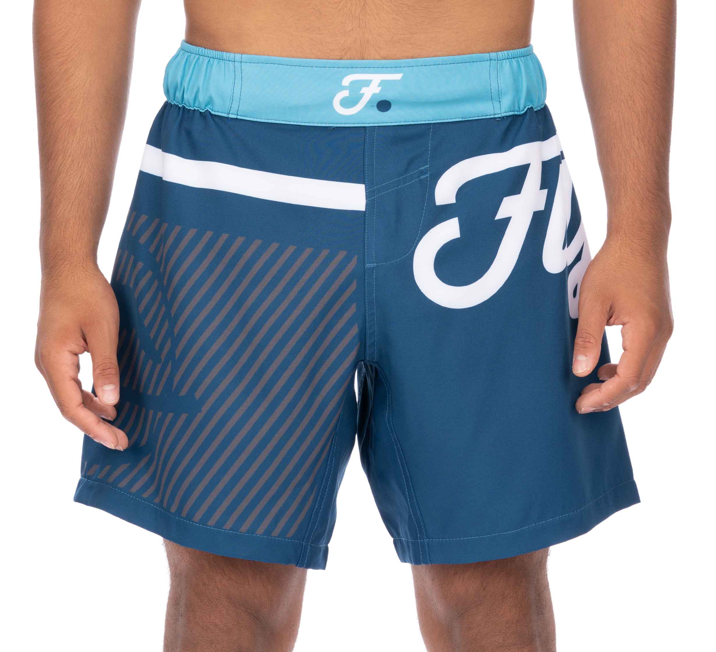 A person wears Script Grappling Shorts Blue, featuring a light blue waistband, white logo, and diagonal stripes on one side. Only their torso and upper legs are visible; their face is not shown.