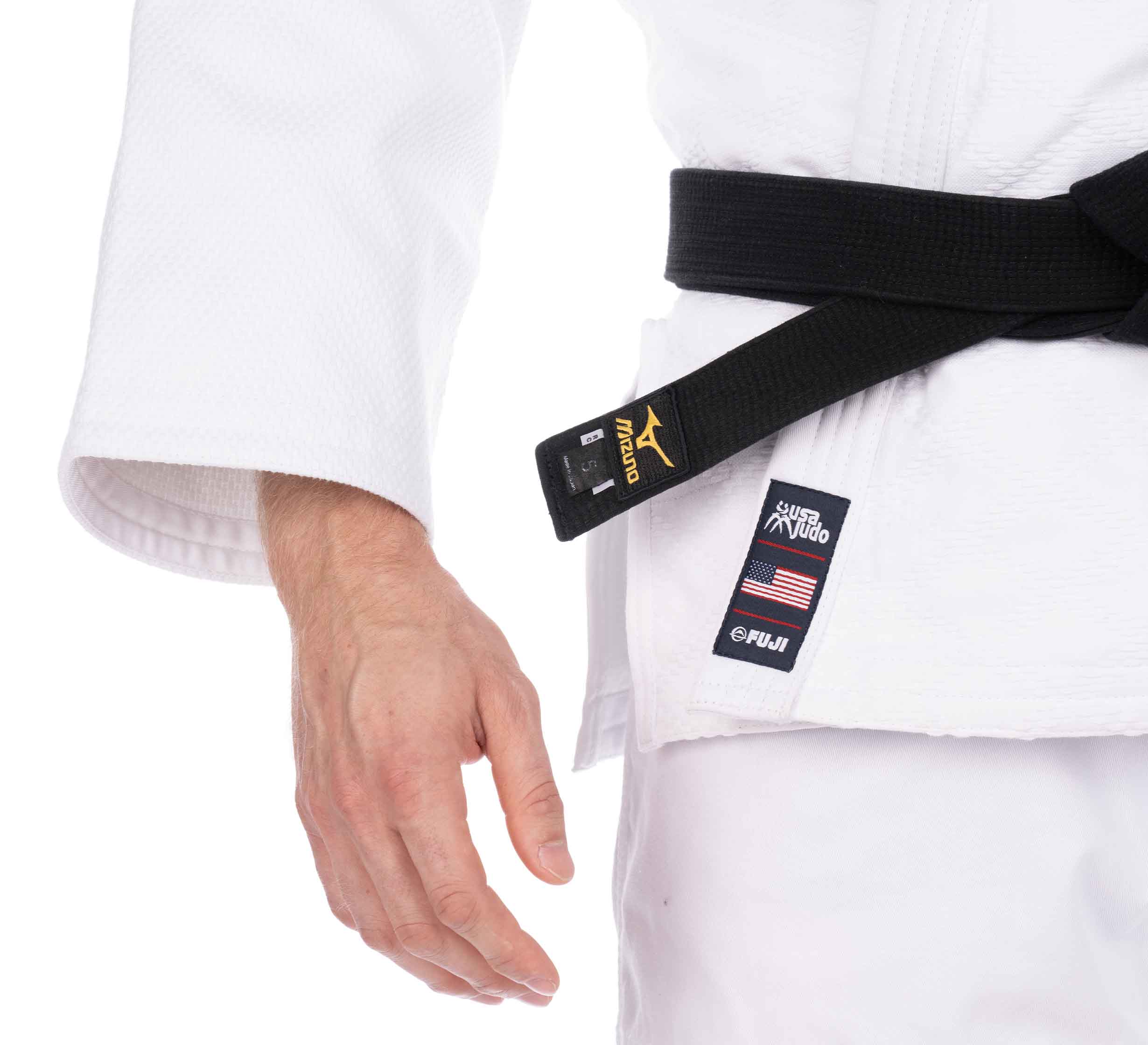 A person wearing the USA Judo Double Weave Gi 2.0 White with a black belt, displaying a close-up of their left hand, jacket details, and patches featuring the American flag and brand logos.