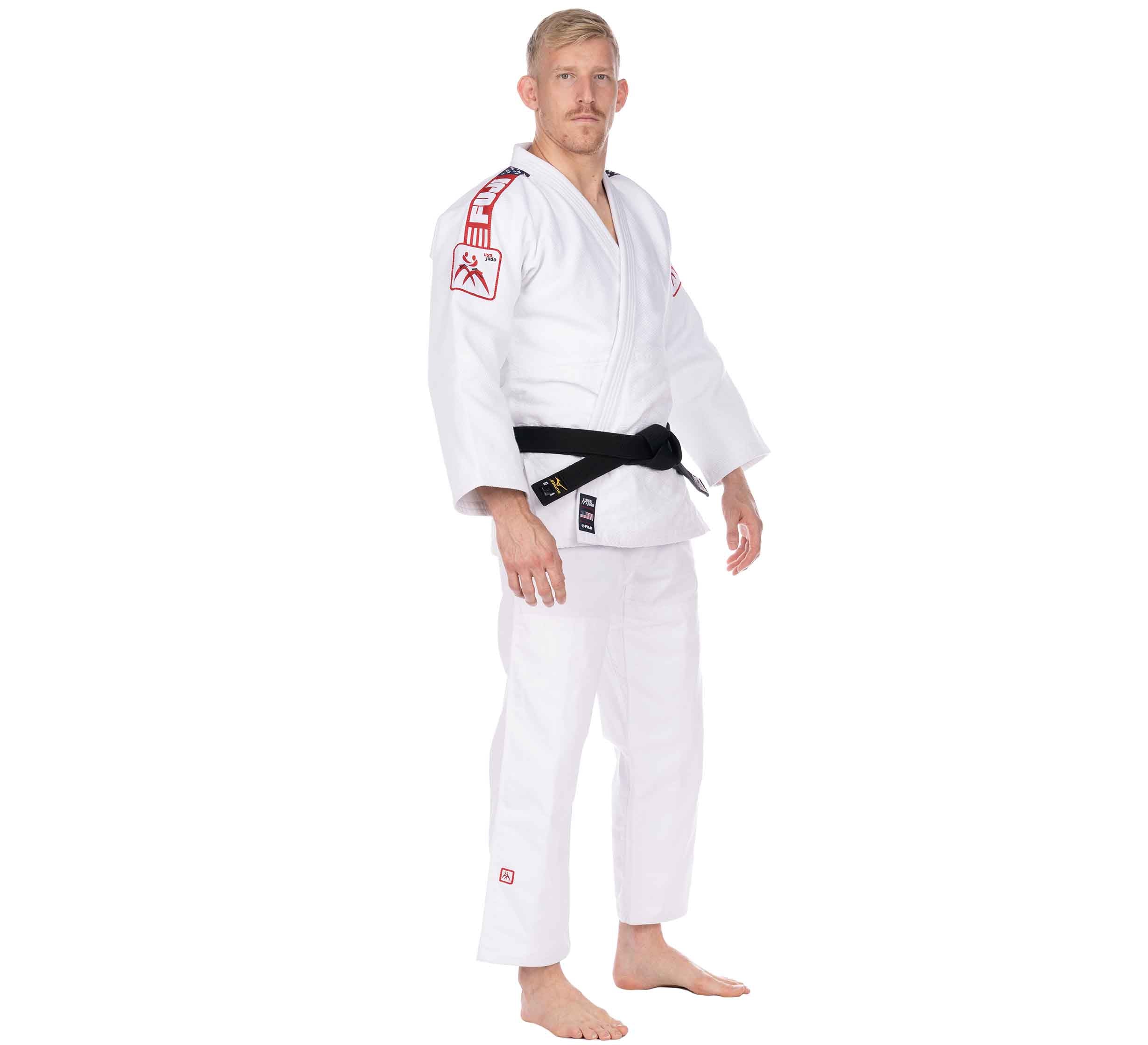 A man in the USA Judo Single Weave Gi 2.0 White with red patches and a black belt stands barefoot against a white background, facing slightly to the side with a neutral expression.