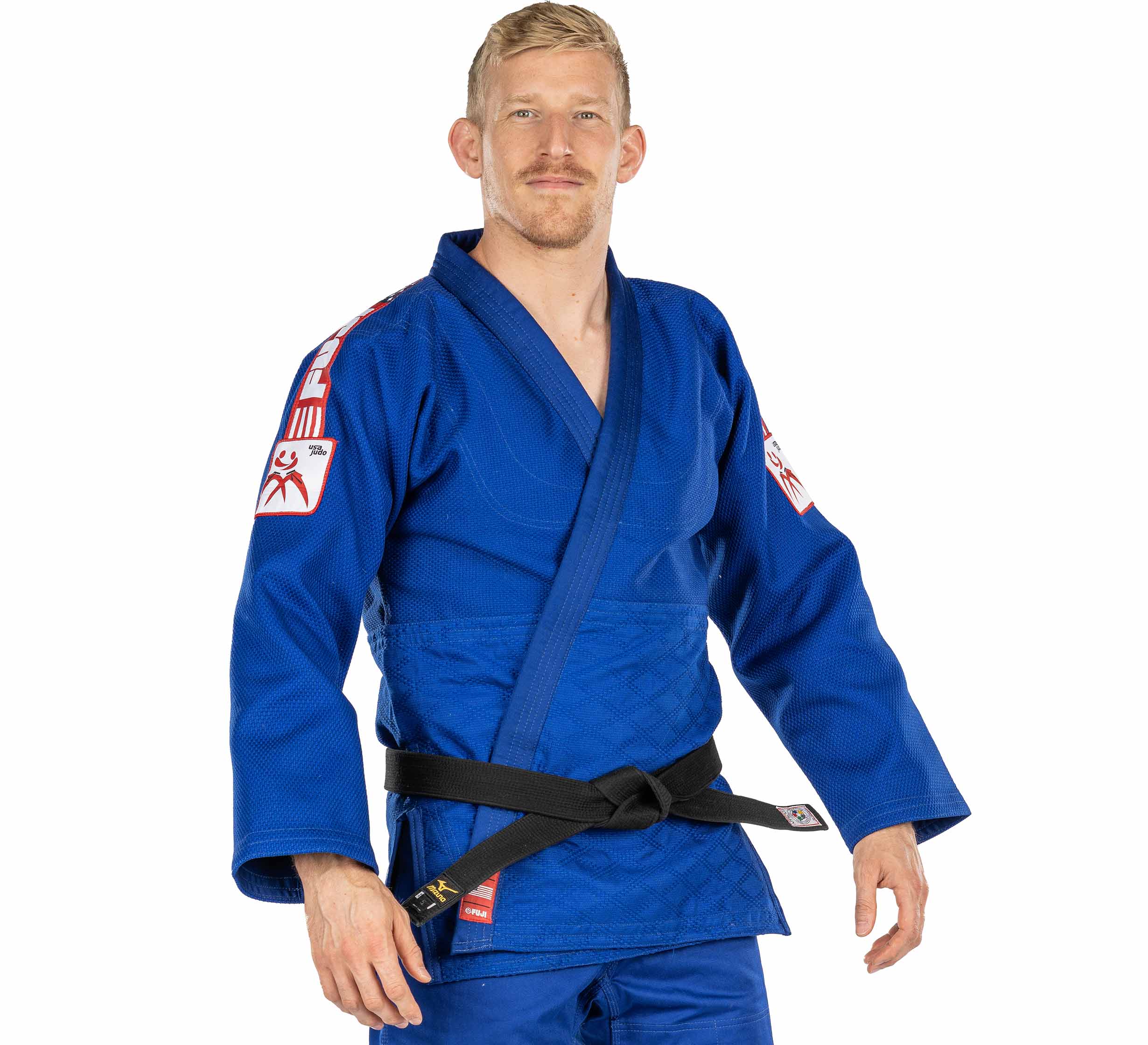 A man wearing the USA Judo Single Weave Gi 2.0 Blue with a black belt stands facing forward, smiling slightly at the camera with his hands relaxed at his sides.