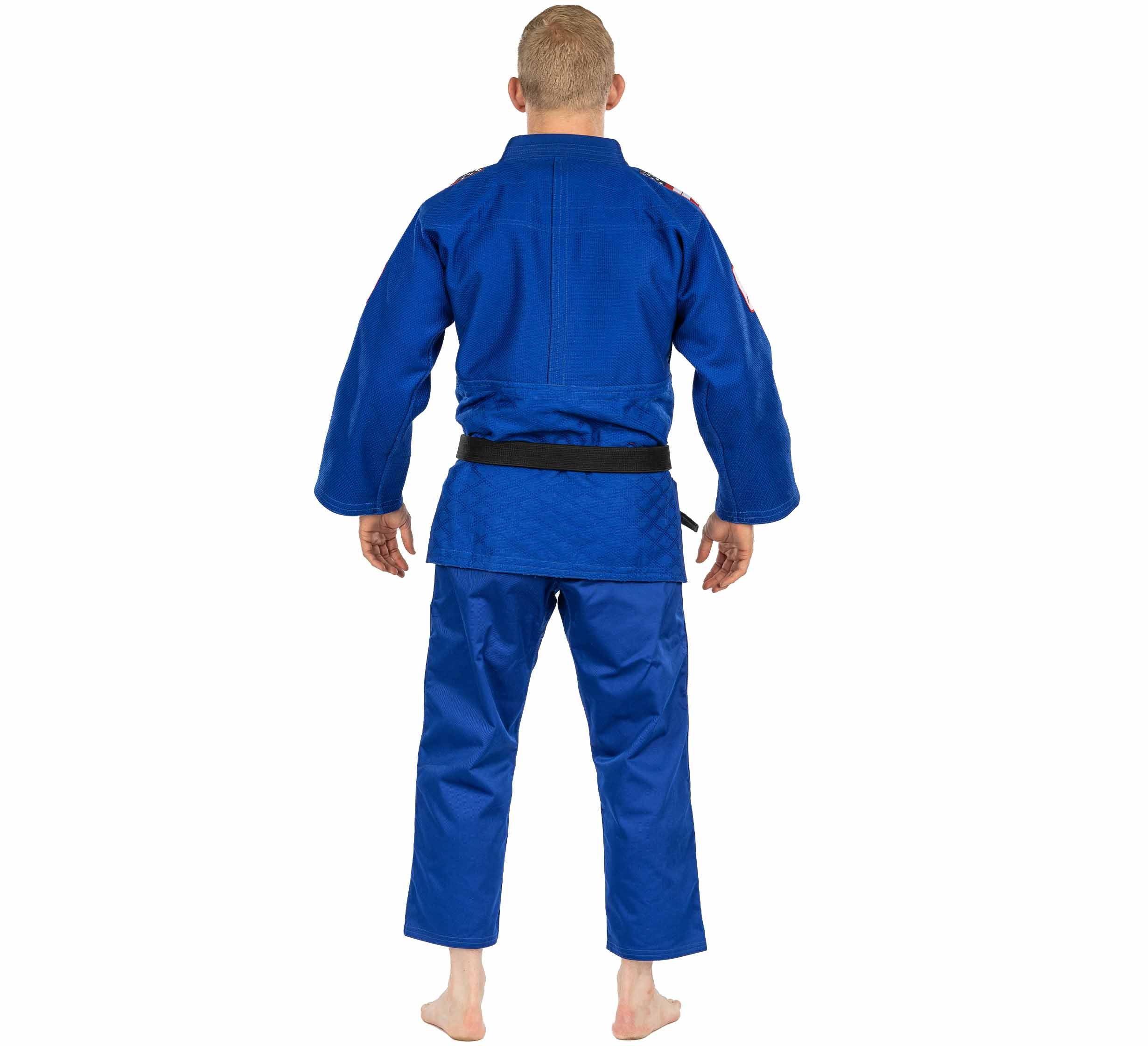 A person with short blond hair, seen from behind, barefoot and wearing a USA Judo Single Weave Gi 2.0 Blue with a black belt, stands against a white background.
