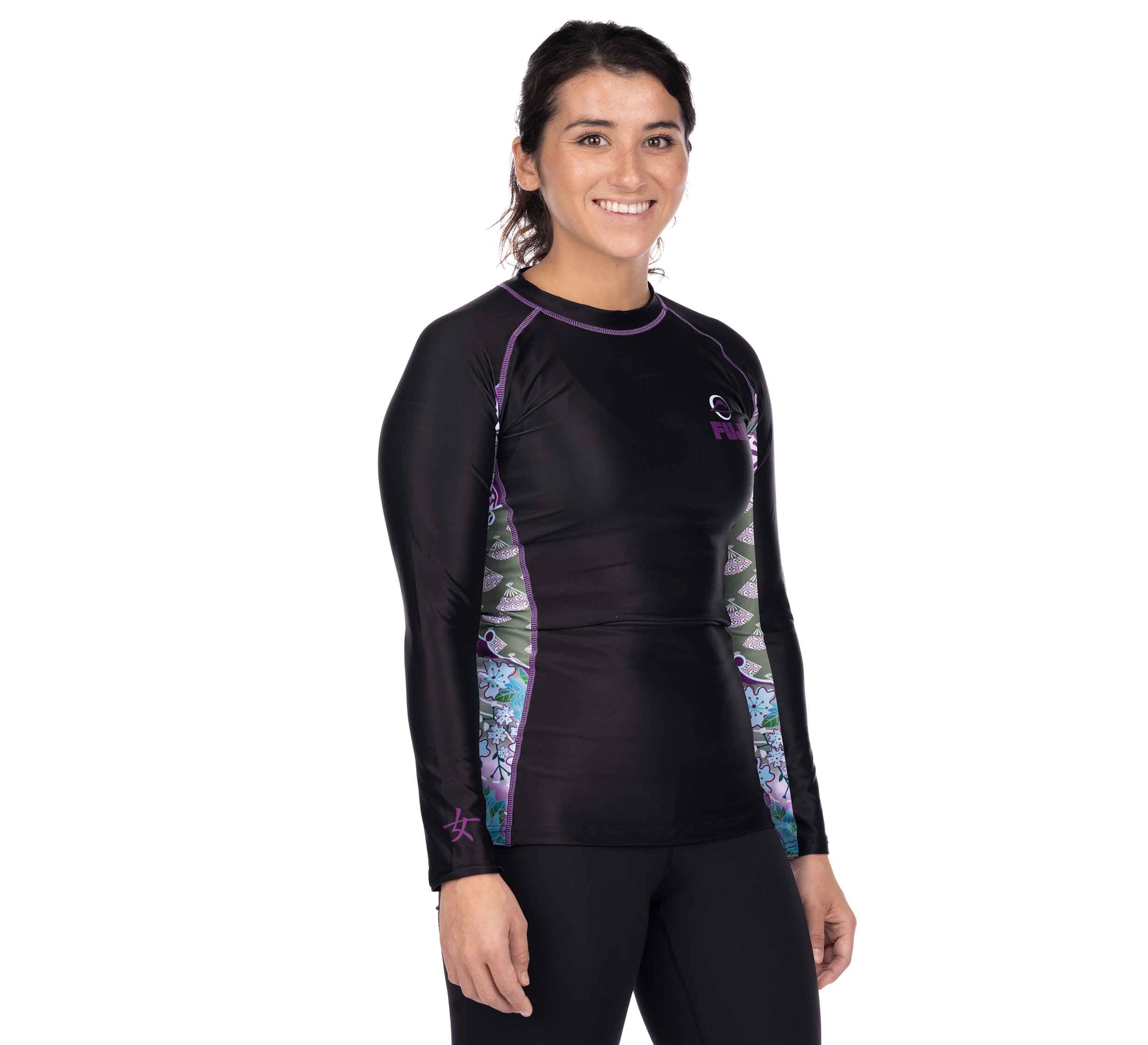 A woman stands smiling, wearing the Kimono Womens Long Sleeve Rashguard Purple and black leggings against a plain white background.