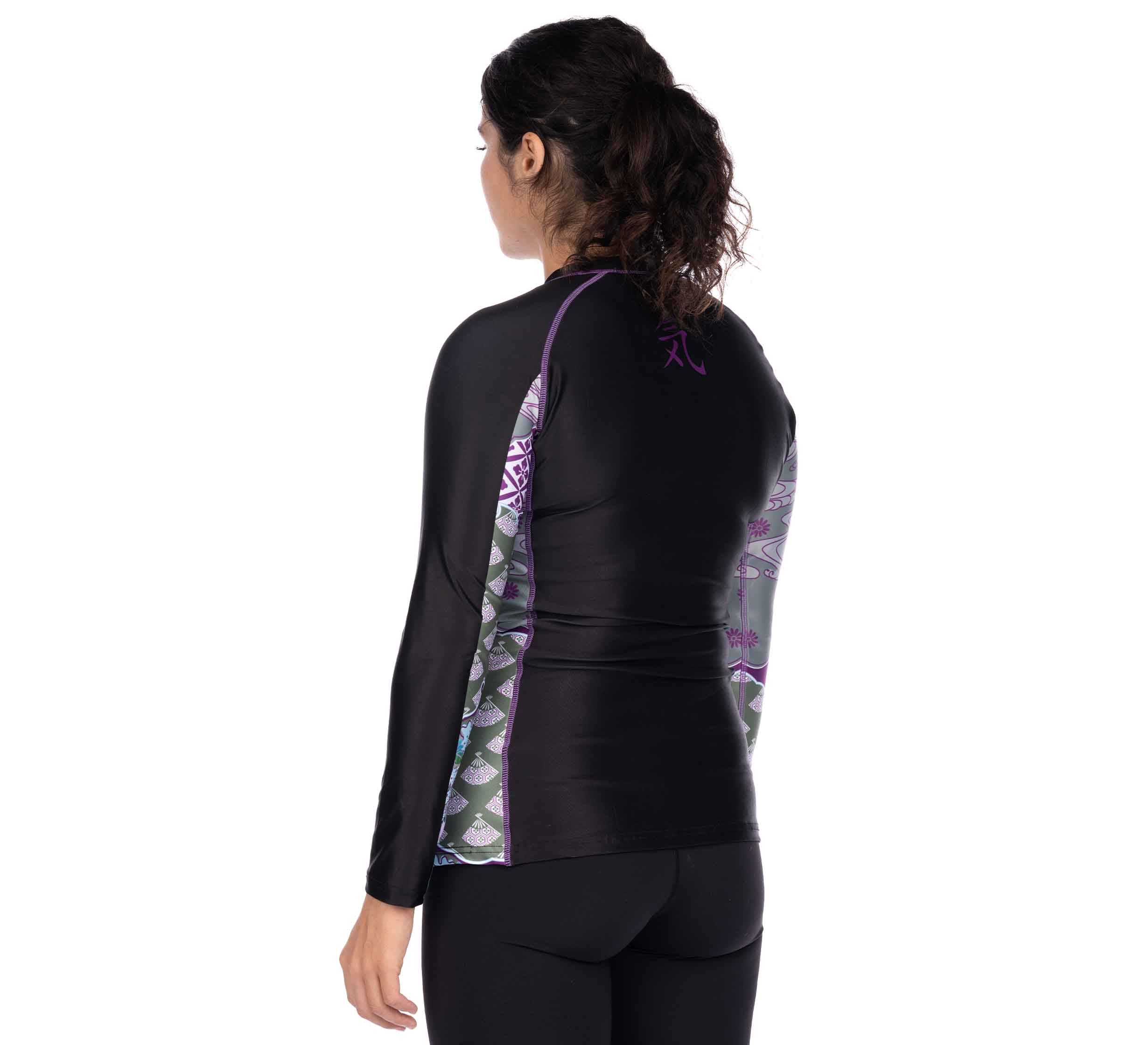 A woman with curly brown hair in a ponytail is shown from the back, wearing the Kimono Womens Long Sleeve Rashguard Purple and black leggings, standing against a white background.