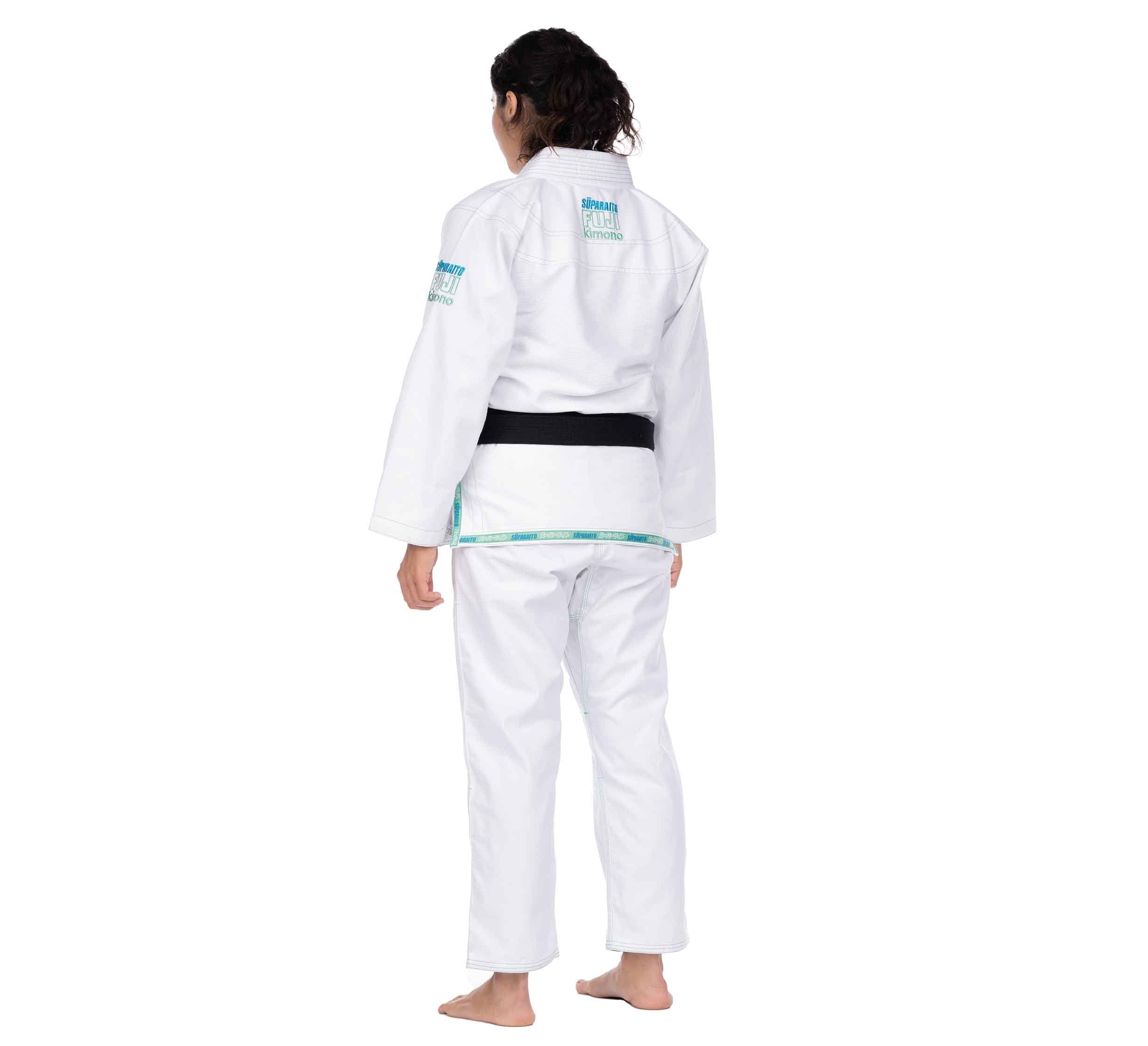 A person with dark hair, barefoot and facing away from the camera, wears a Suparaito Girl's BJJ Gi in teal against a plain white background.