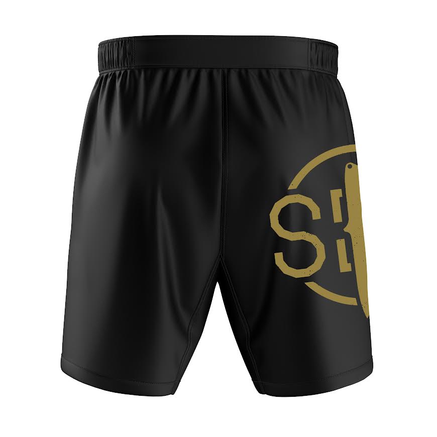 The Sheepdog Response Essential Shorts in black feature an elastic waistband and a large gold circular SB logo with part of a vertical graphic on the right leg.