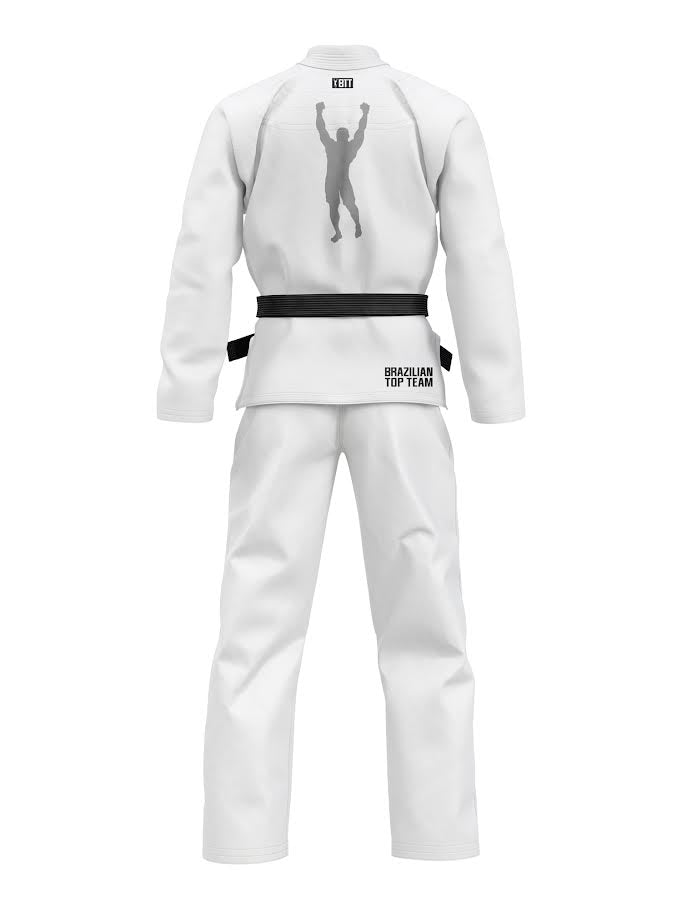 The Kids BTT 25th Anniversary Ultra Lite White gi, shown from the back, features a black belt and a raised-arms silhouette on the upper back with "Brazilian Top Team" text on the lower back.