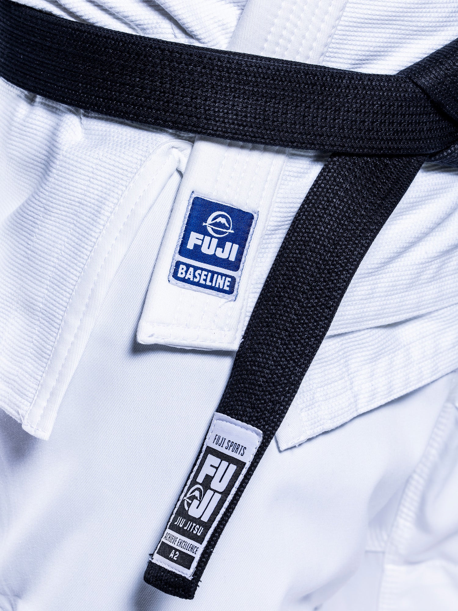 Close-up of the Baseline 2.0 BJJ Gi White Navy with two FUJI patches and a tied black belt, highlighting the fabric texture and stitching details.