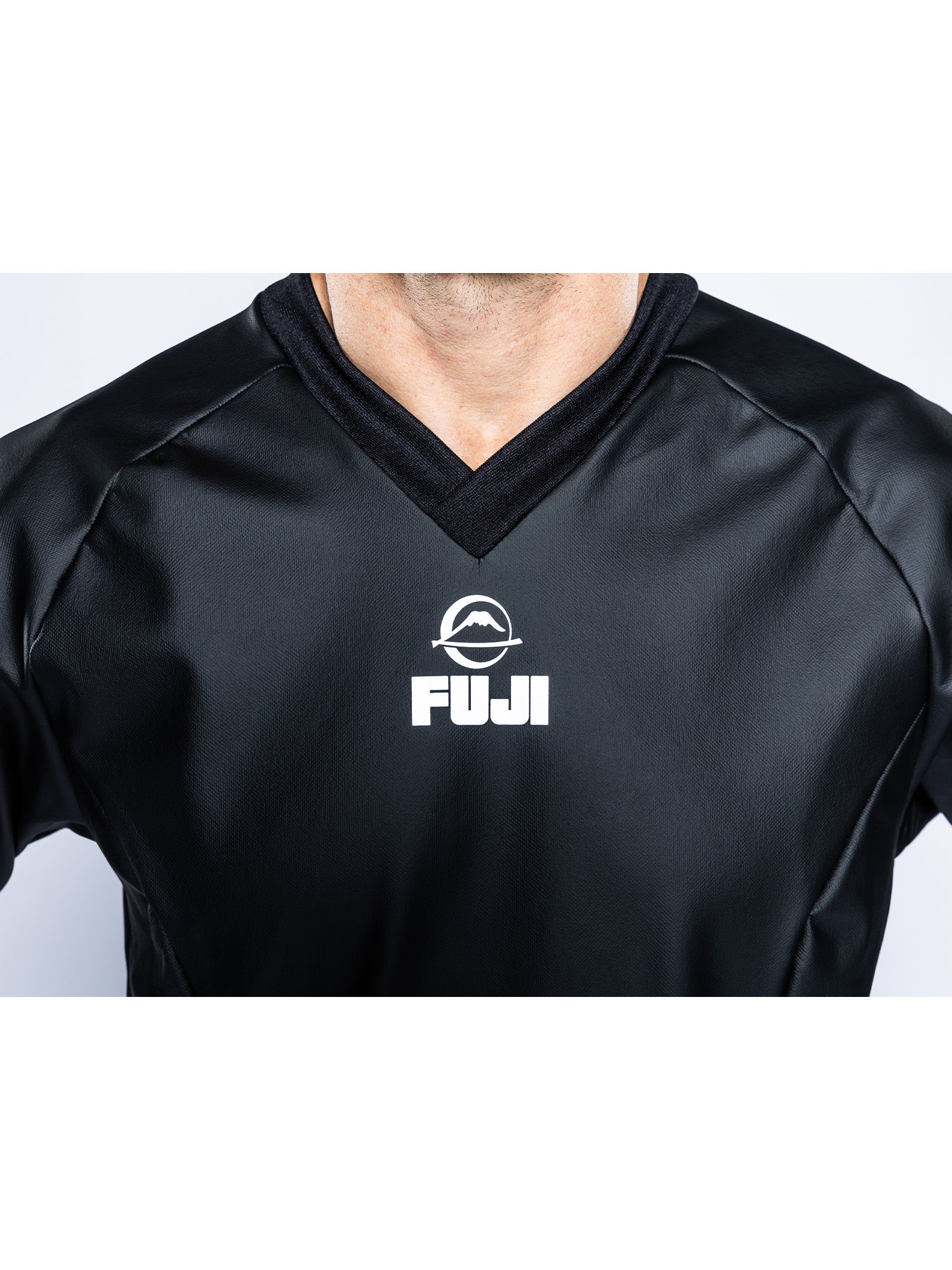 A person wearing the Grappling Sauna Suit Black, featuring a white FUJI mountain logo on the upper chest. Only their shoulders, upper chest, and neck are visible.