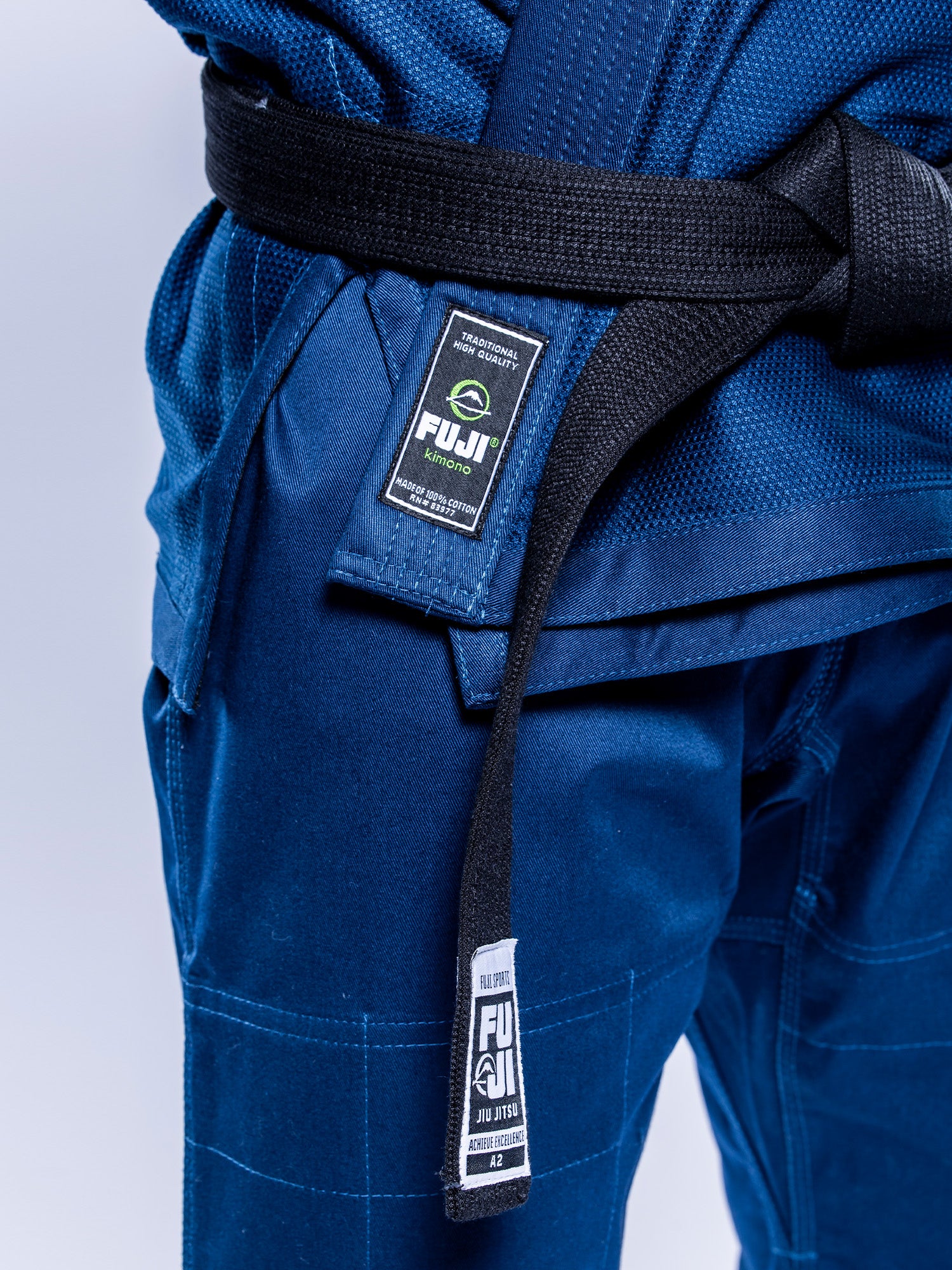 A person wearing a Lightweight BJJ Gi Navy with a black belt, both featuring visible FUJI branding.