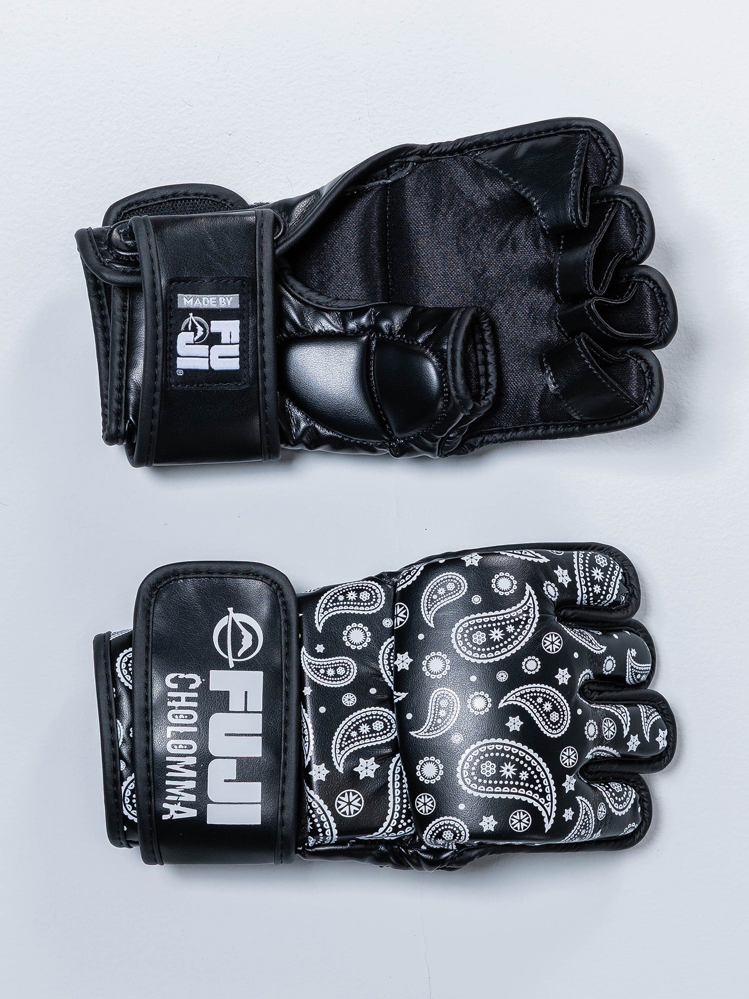Two black CholoMMA Paisley MMA Gloves rest on a light surface—one displays the palm, the other the back with white paisley and geometric designs, plus FUJI and CHAOMMA branding.