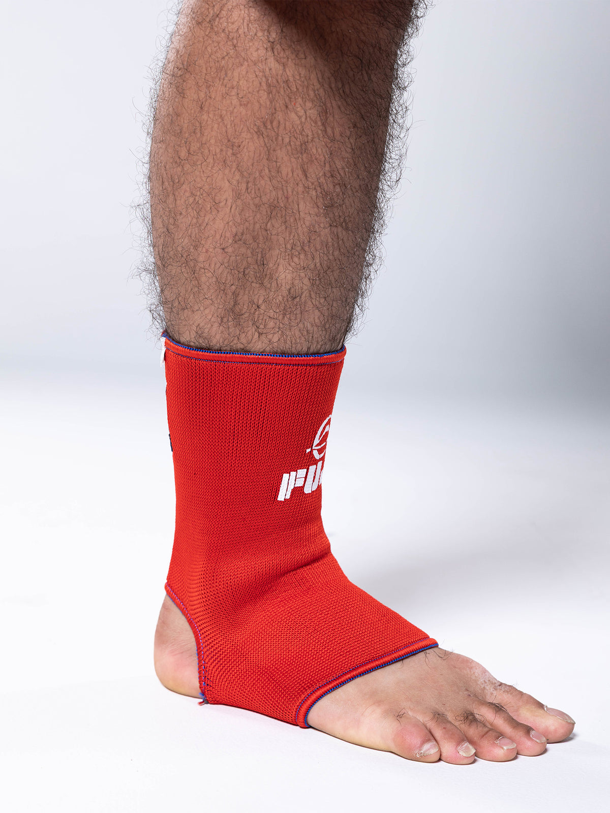 A person’s lower leg and foot are shown wearing the FIAS Sambo Beach Ankle Support Reversible in bright red against a plain white background, with only the leg and foot visible.