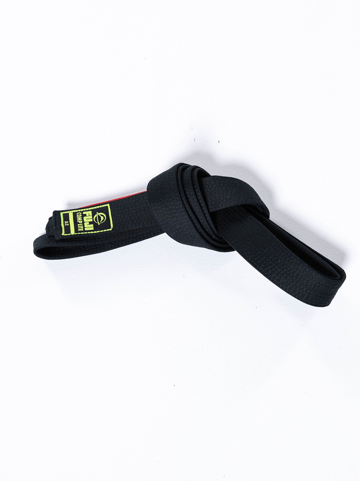 The BJJ Comp Lite Belt Black, featuring a green and yellow label and tied in a knot, is displayed on a white background.