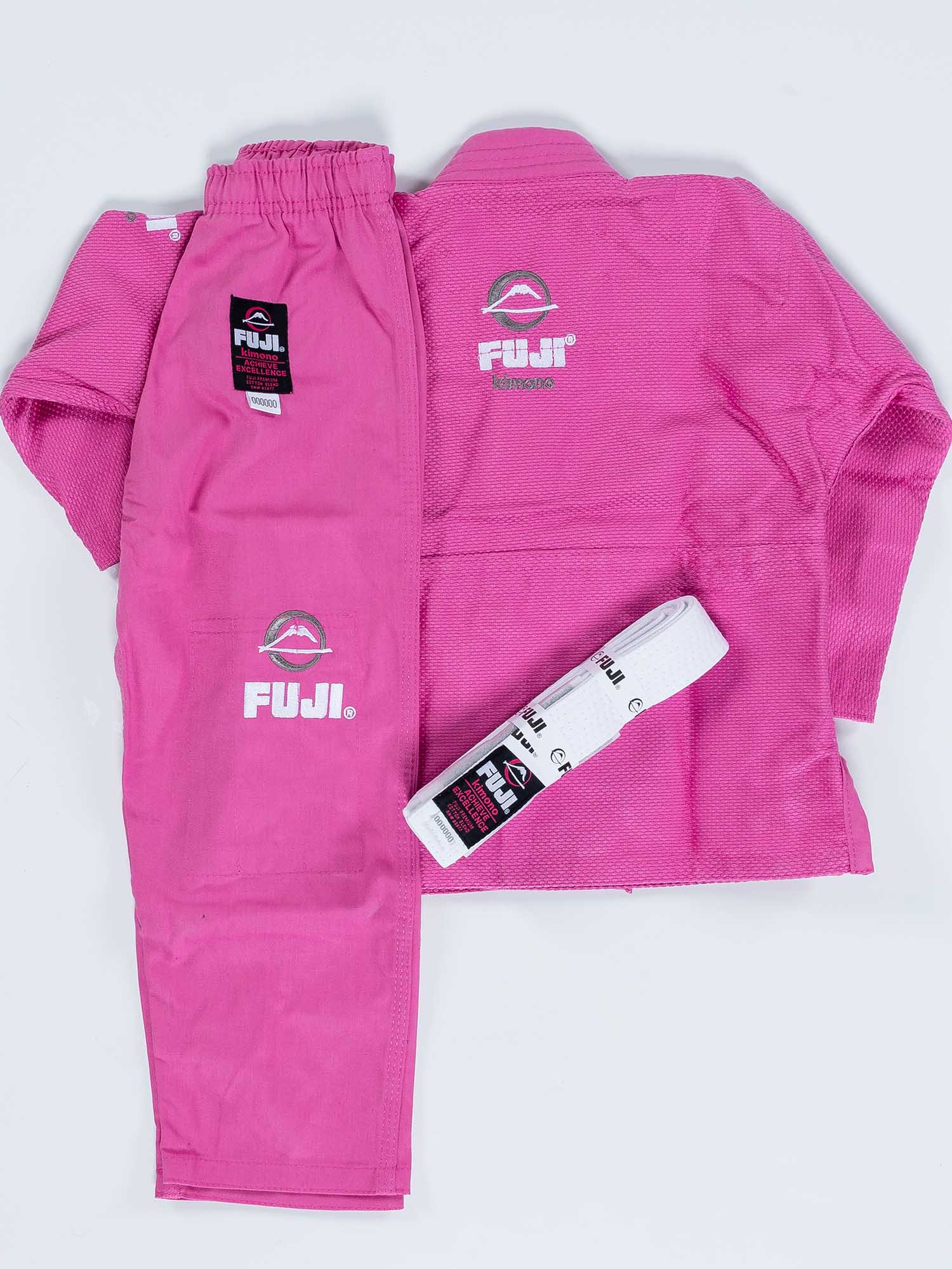 A FUJI Baby Judo Gi set in pink is laid out flat, displaying the jacket, pants, and a folded white belt. Both pieces feature FUJI logos and brand tags.