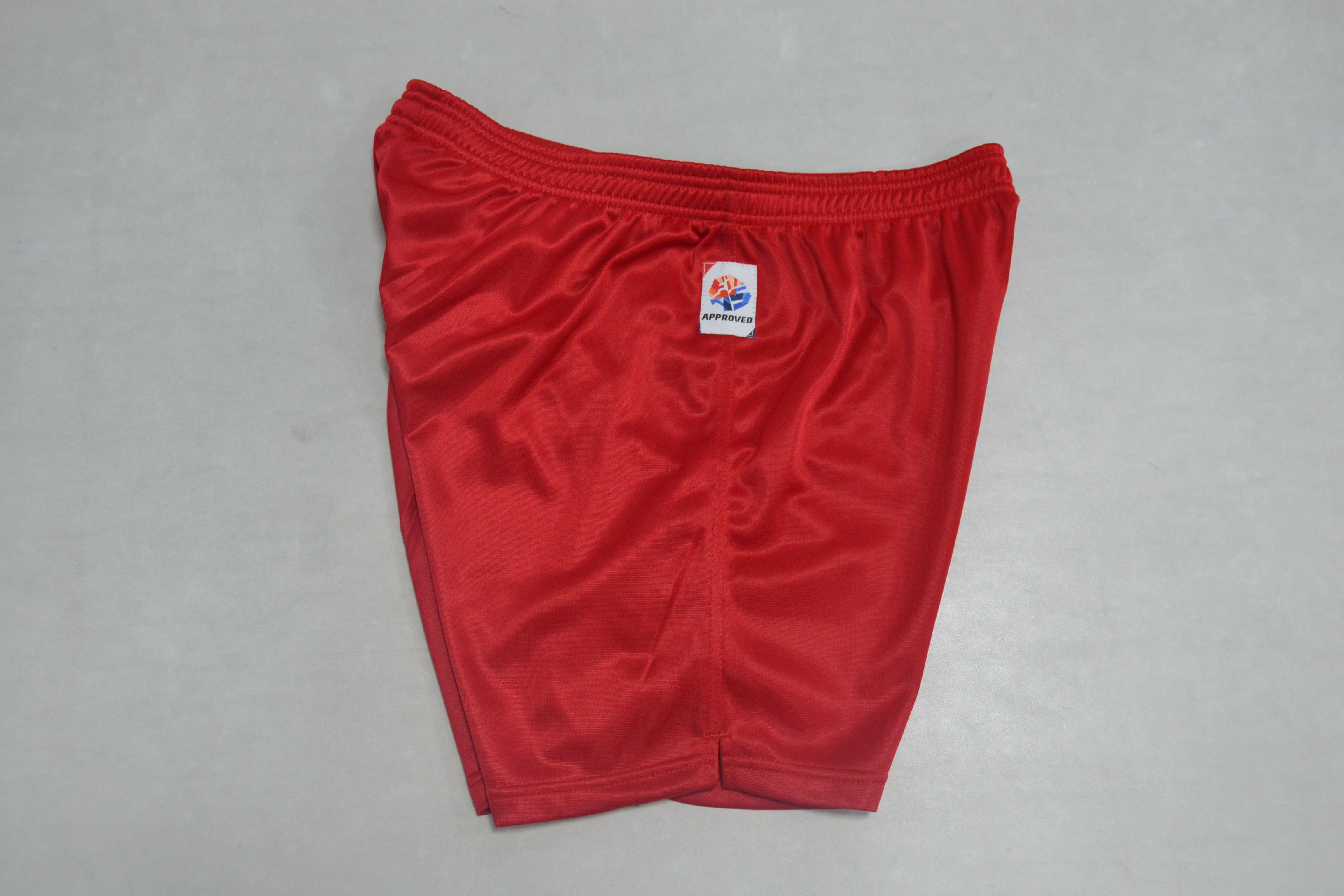 A pair of FIAS Sambo Shorts Red is neatly folded on a plain, light-colored surface, featuring a small white label with a logo on the waistband.