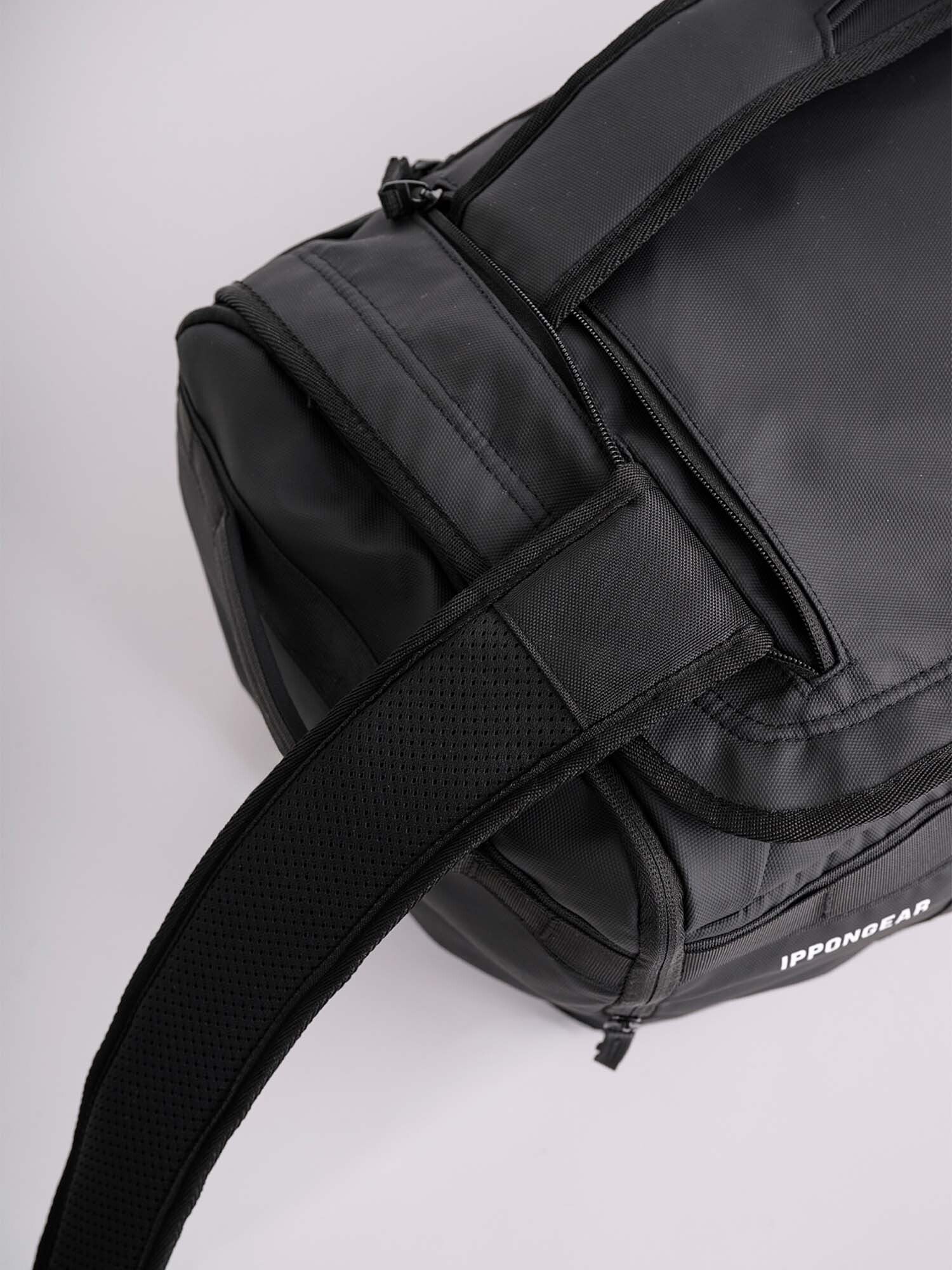A close-up of the IPPONGEAR 2 in 1 Sports Bag Black with padded shoulder straps and the IPPONGEAR logo visible on the side.