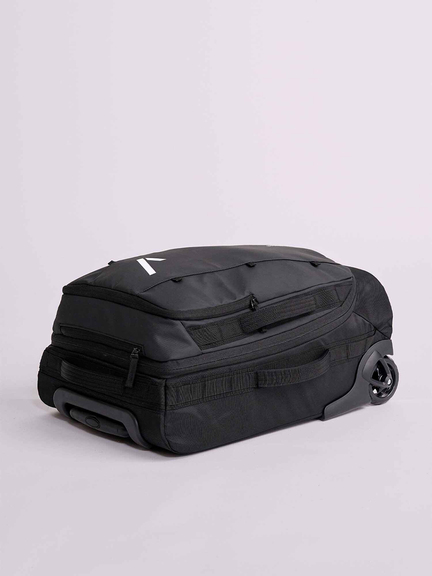The IPPONGEAR Travel Trolley Black M is a large black rolling duffel bag with two wheels and multiple zippered compartments, displayed on a light gray background.