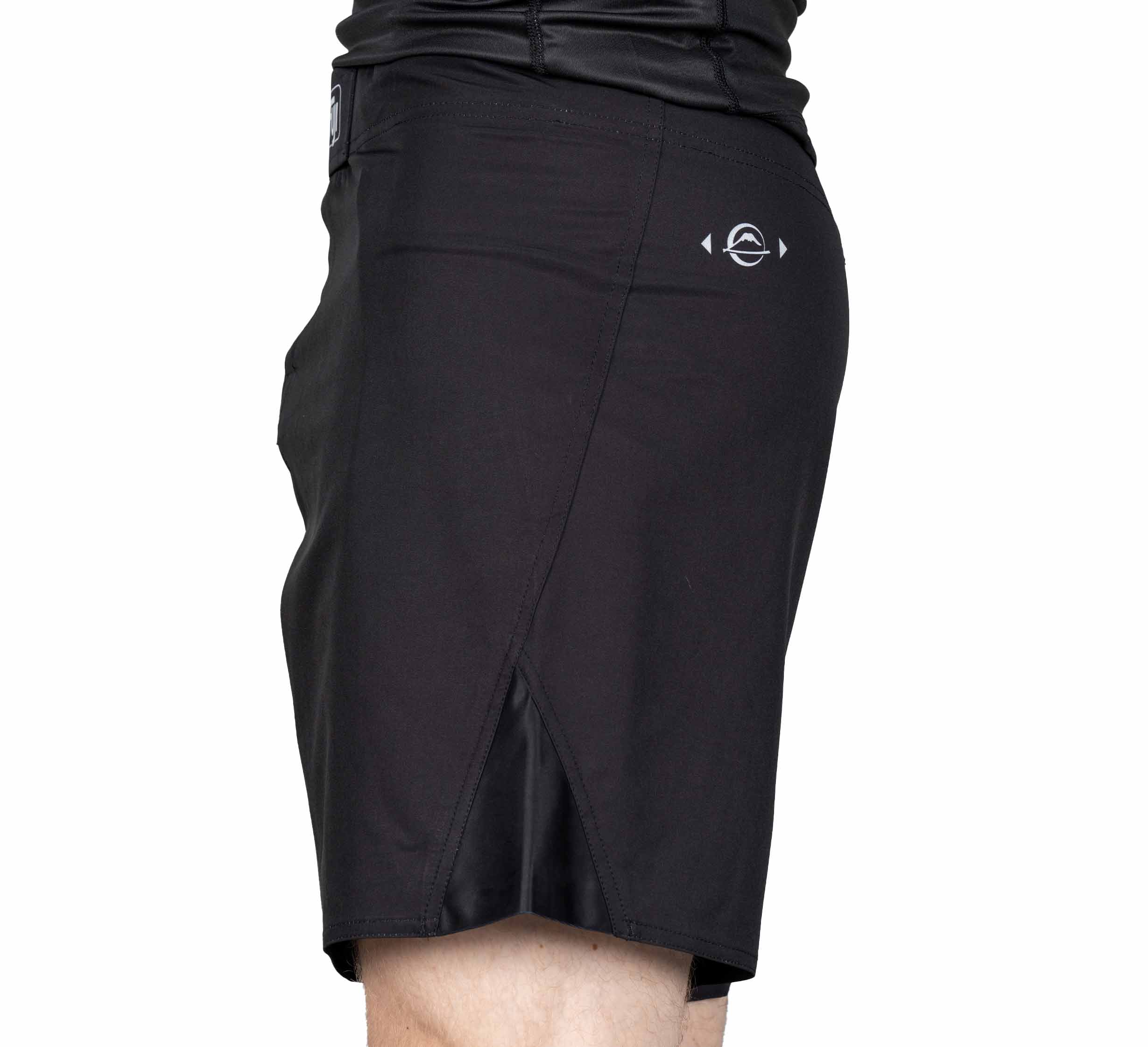 Person wearing Pro-Tech Grappling Fight Shorts, black with a small white logo on the back and a side slit, shown from the side against a white background.